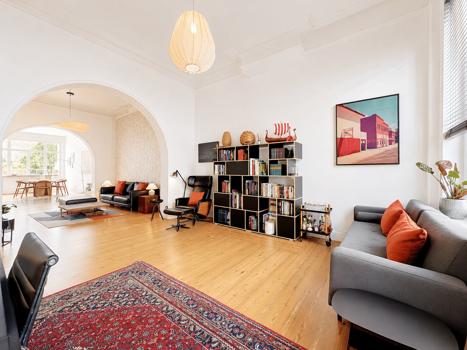 Salon Lumineux aux Hauts Plafonds – You Real Estate Agency Salon lumineux d’appartement avec hauts plafonds, arches élégantes et parquet en bois.