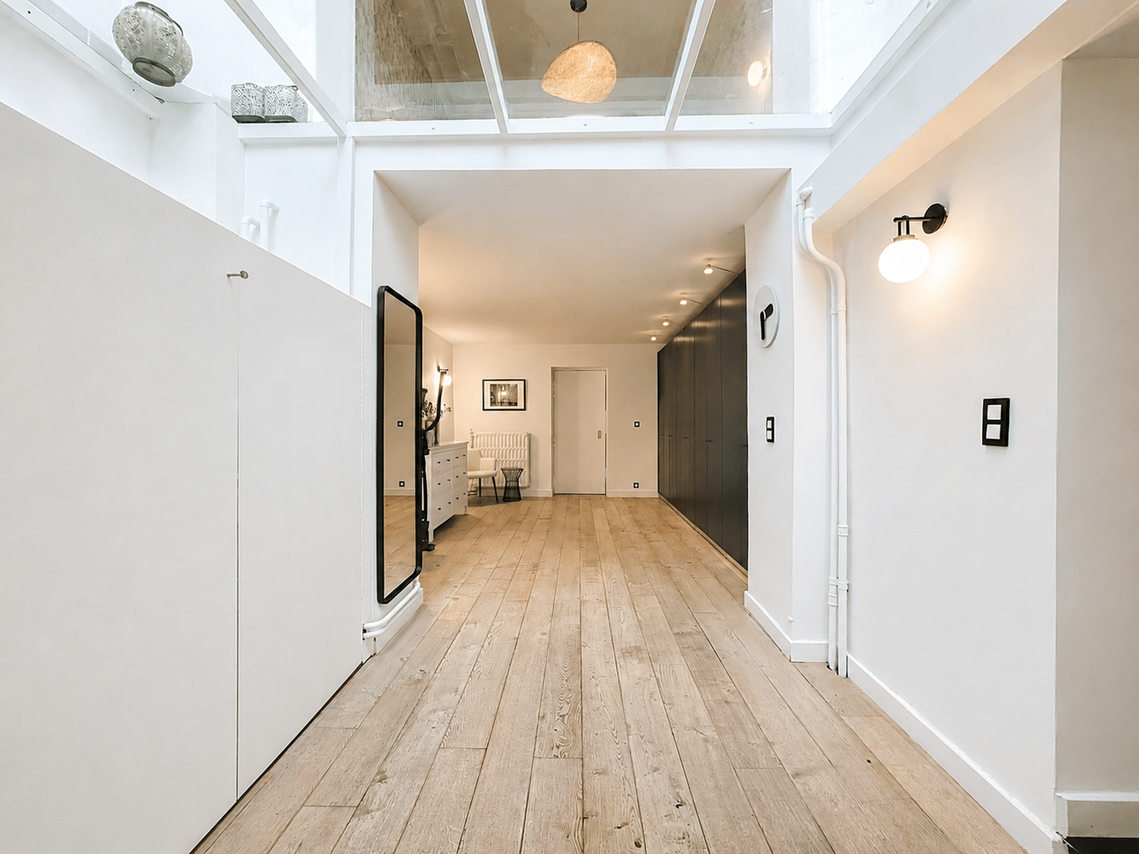 Couloir Moderne avec Verrière – You Real Estate Agency Couloir moderne d’appartement avec parquet clair, verrière, rangements intégrés et éclairage design.