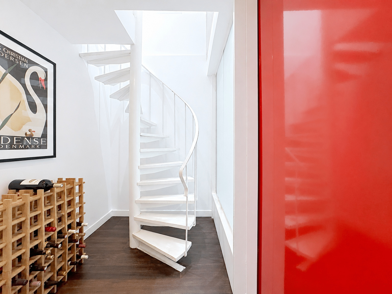 Escalier en Colimaçon avec Cave à Vin – You Real Estate Agency Intérieur de maison lumineuse avec escalier en colimaçon blanc et cave à vin.