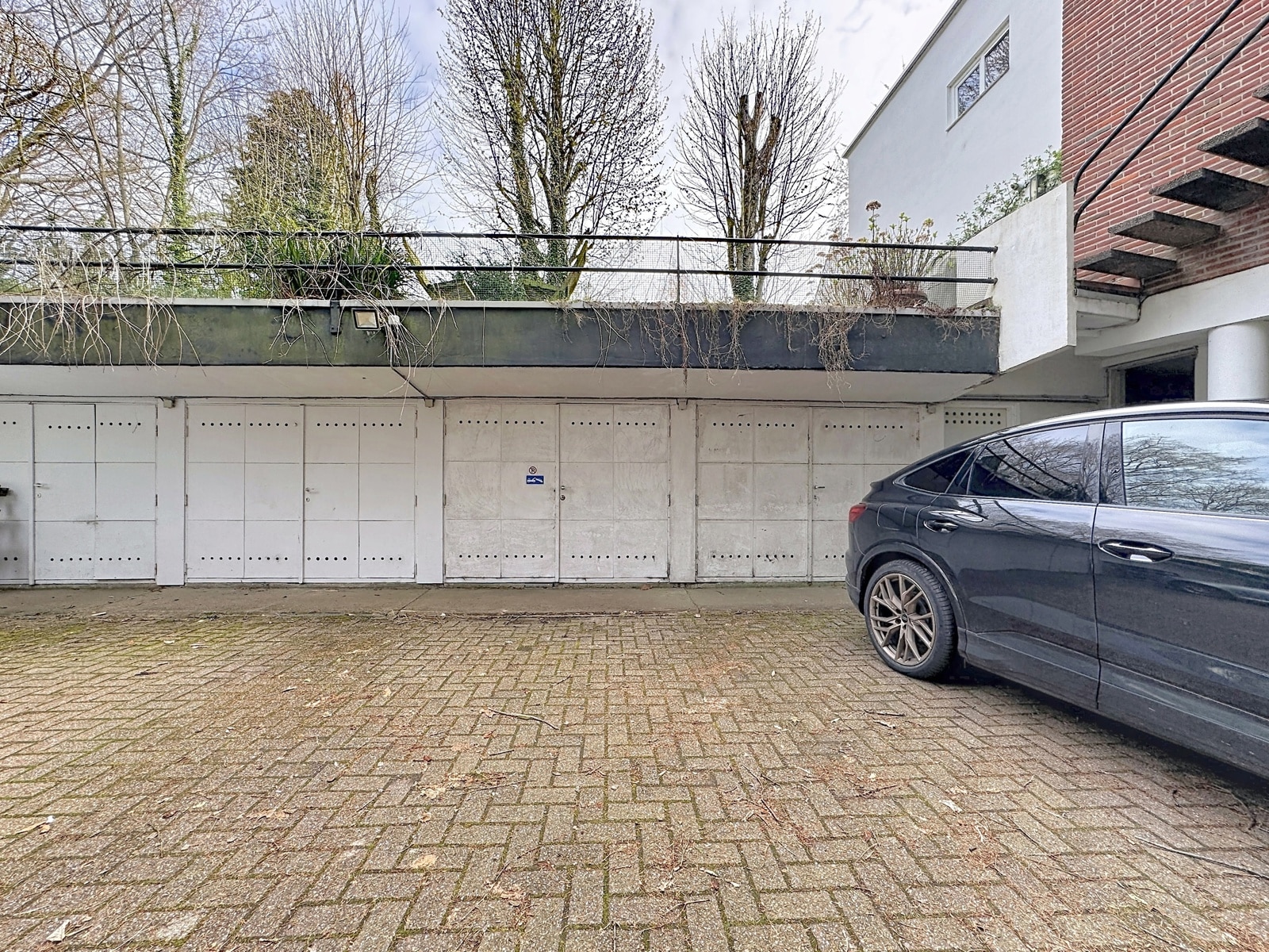 Garages and Residential Parking – You Real Estate Agency Private garages and parking lot for a residential building with a tree-lined terrace.