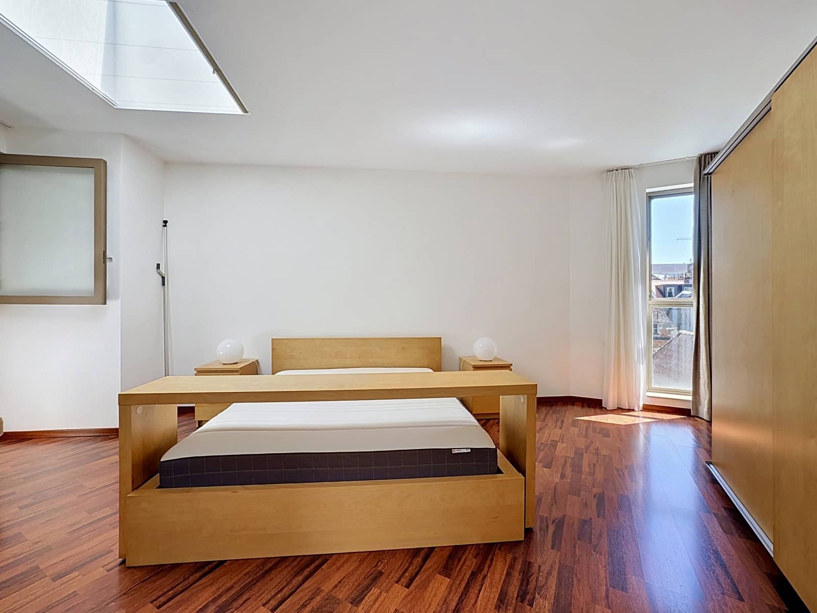 whise photo 10 Minimalist bedroom with a wooden platform bed, two nightstands with round lamps, and a large window with sheer curtains.