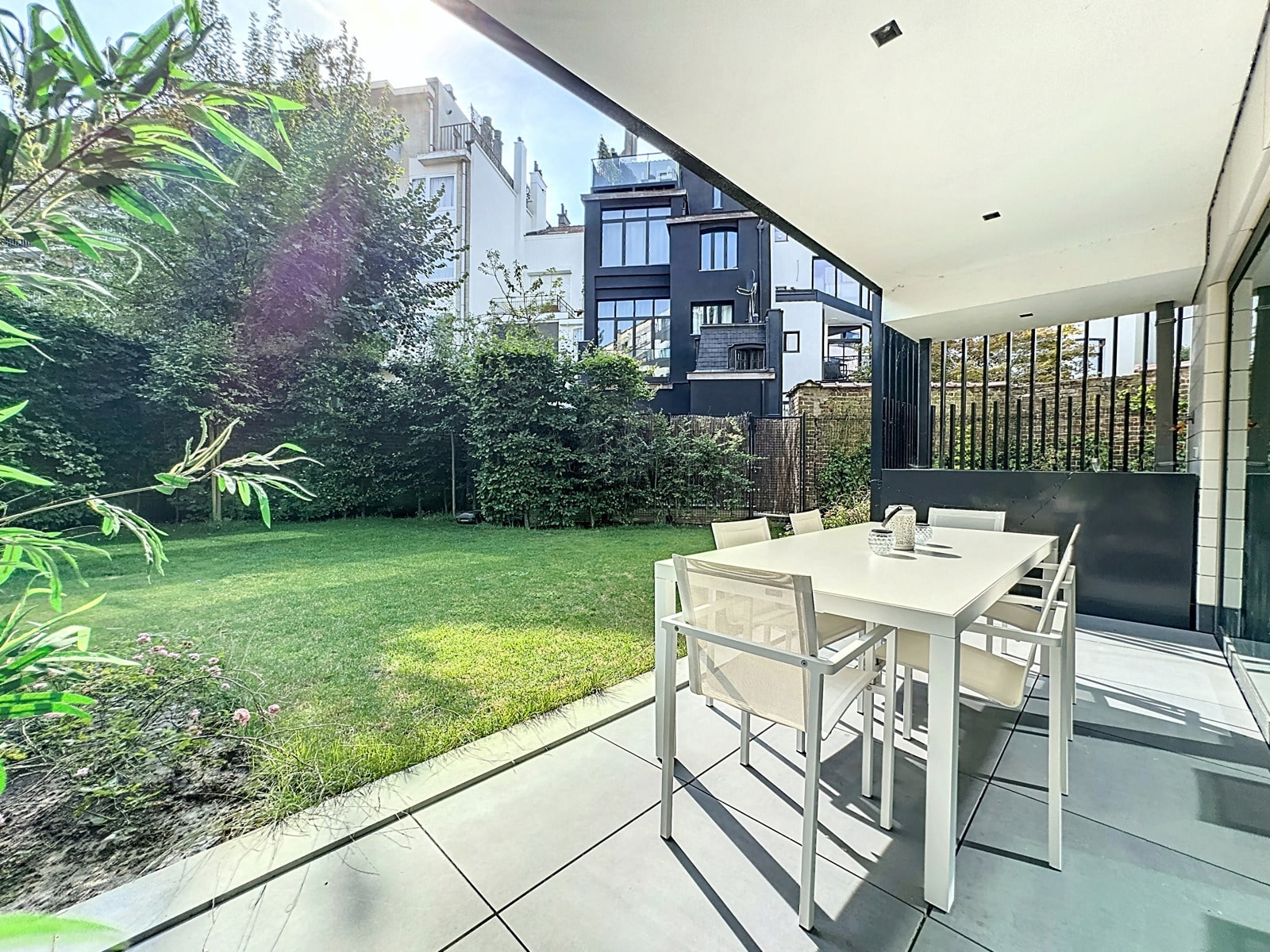 Terrasse Moderne Avec Jardin Verdoyant – You Real Estate Agency Terrasse moderne avec table à manger et jardin verdoyant de maison contemporaine.