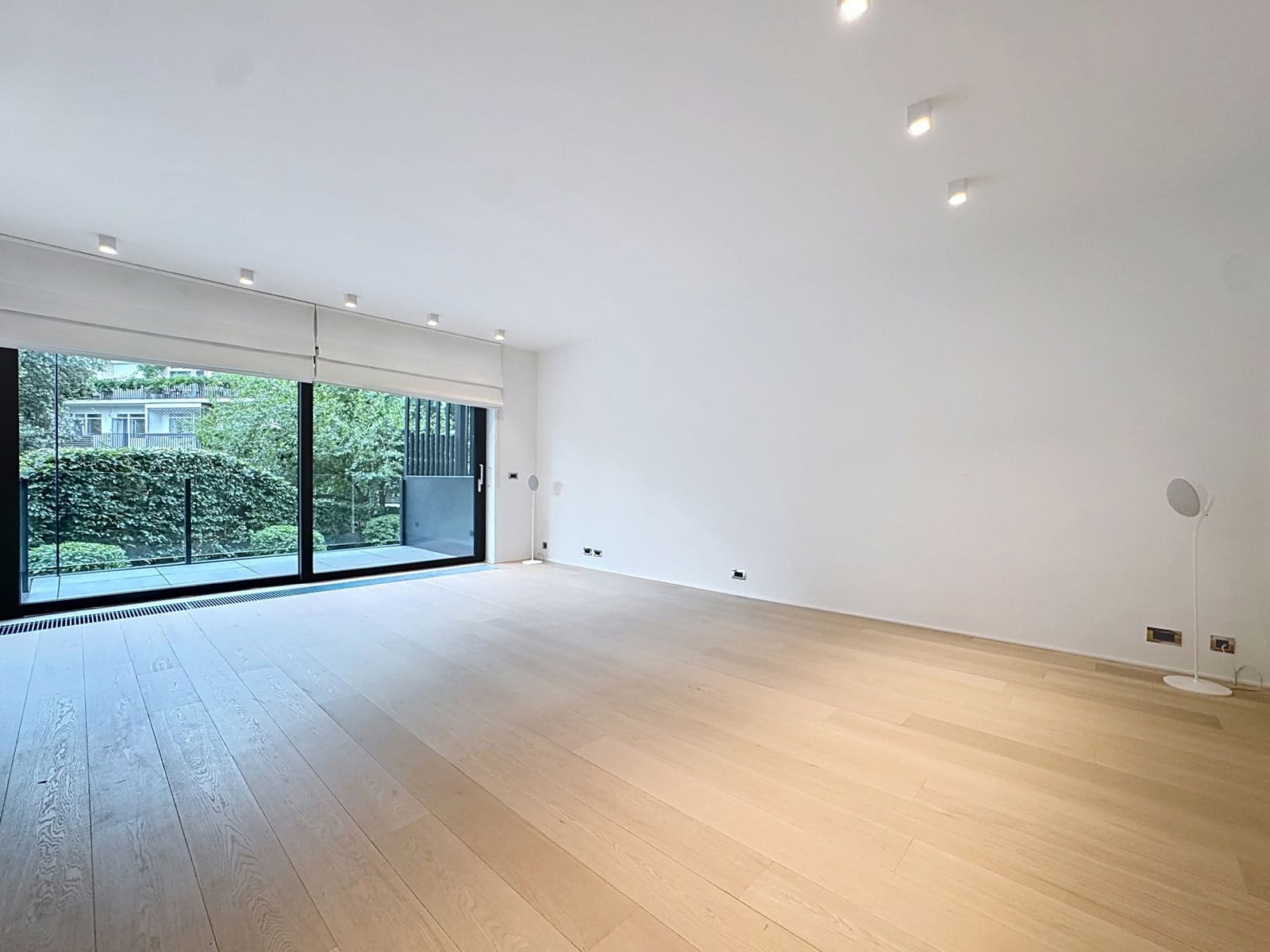 Salon Lumineux avec Baie Vitrée – You Real Estate Agency Salon lumineux d’appartement avec parquet, baie vitrée et terrasse verdoyante.
