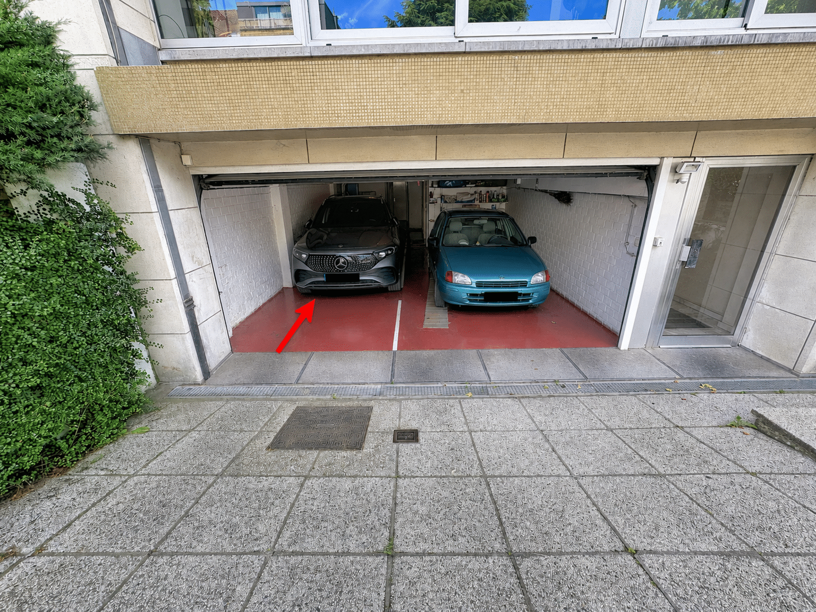 whise photo 12 Two cars parked in a two-car garage: a black Mercedes on the left and a blue compact car on the right, with a red arrow pointing to the left car.