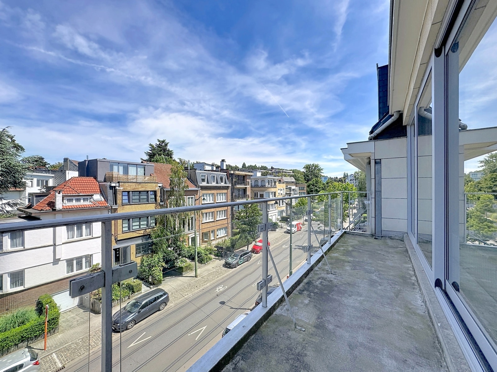 Balcon avec Vue Dégagée – You Real Estate Agency Terrasse d’appartement avec vue dégagée sur quartier résidentiel et maisons.