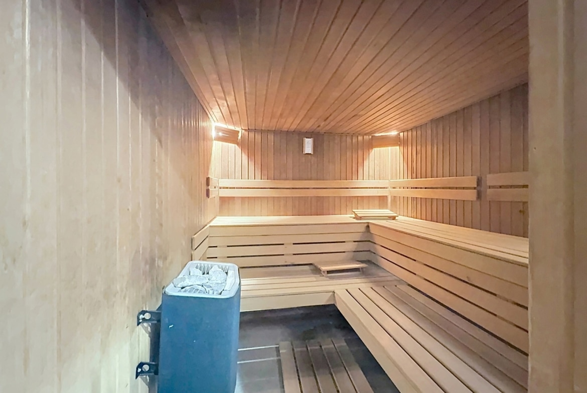 Privésauna van hout in een huis, met zitbanken en een kachel.