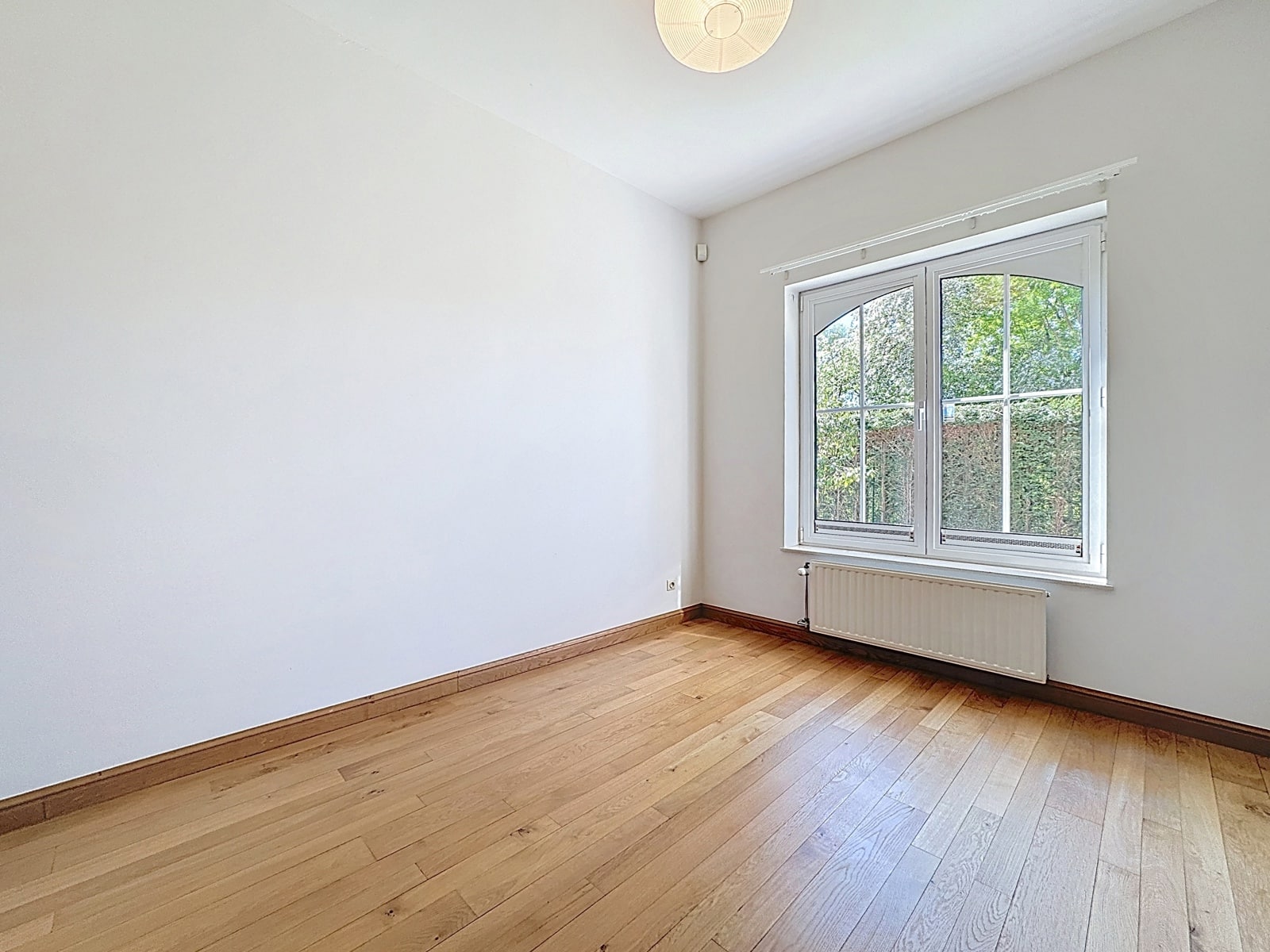 Chambre Lumineuse avec Parquet – You Real Estate Agency Chambre lumineuse avec parquet et grande fenêtre dans appartement.