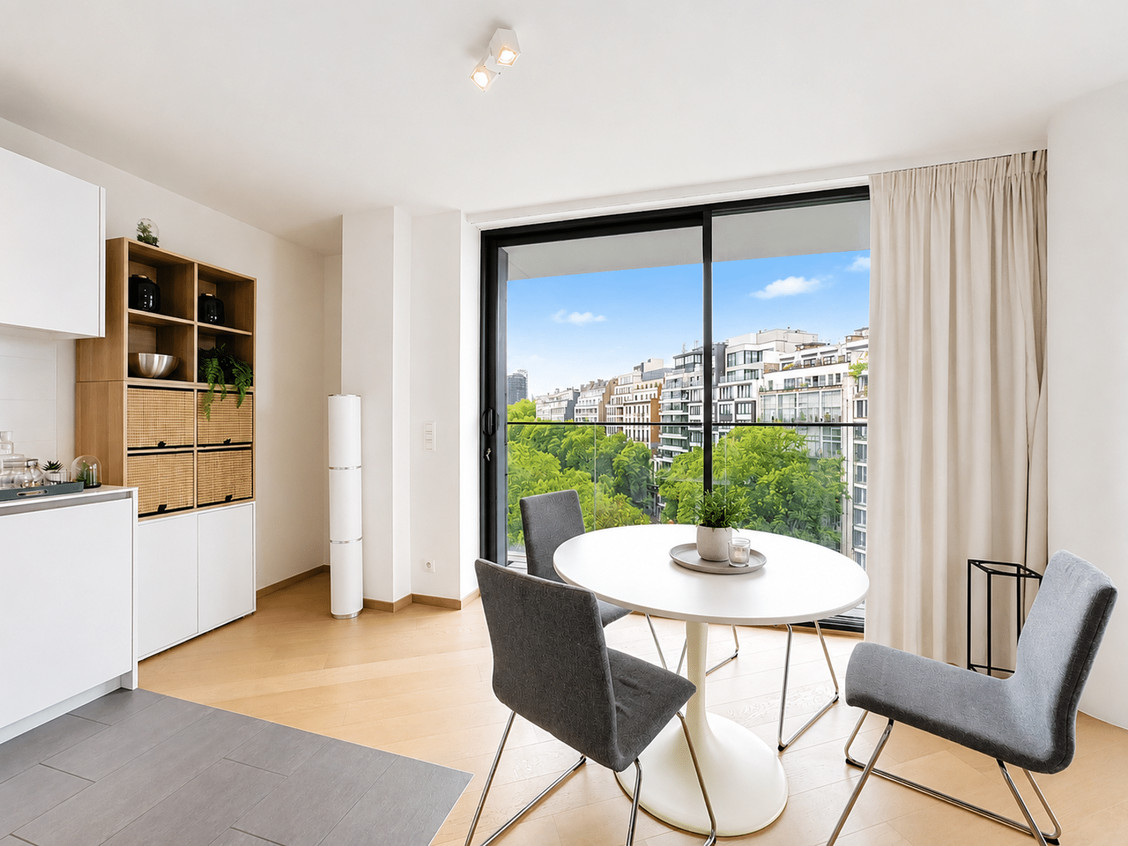 Salle à Manger Lumineuse avec Balcon – You Real Estate Agency Salle à manger moderne d’appartement avec cuisine ouverte et balcon vue ville.