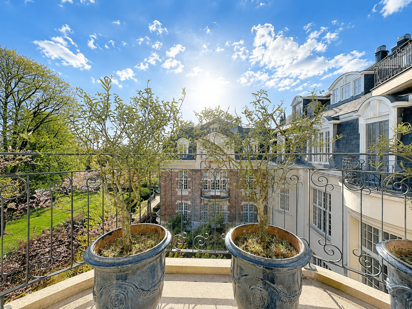 Elegant Balcony with a View of the Garden – You Real Estate Agency Apartment terrace with blue planters and a view of a luxury residential complex.