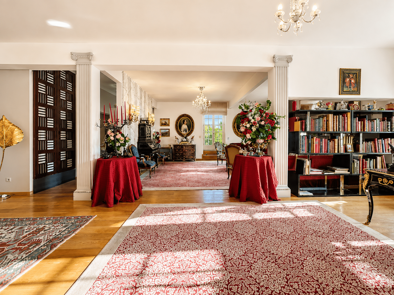 Elegant Living Room with Columns – You Real Estate Agency An elegant living room in a classic home, featuring columns, hardwood floors, a rug, and a bookcase.