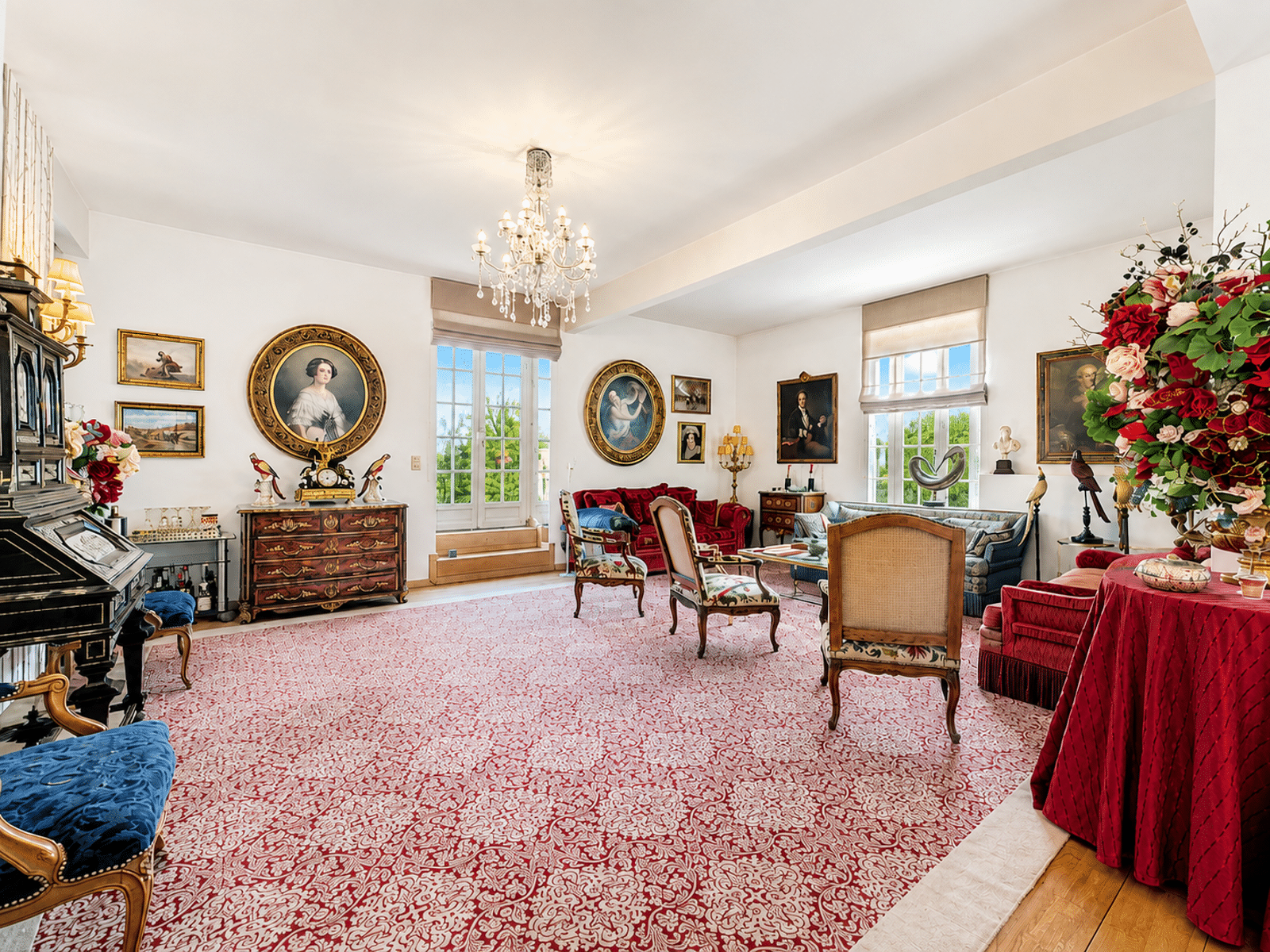 Bright, Classic Living Room – You Real Estate Agency A bright, classic living room with a chandelier, a red rug, and antique furniture.