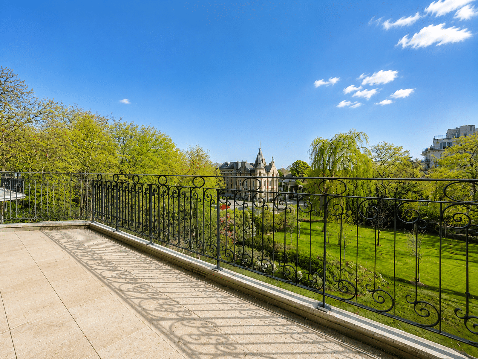 Terrace with a View of the Landscaped Garden – You Real Estate Agency Apartment terrace with a view of a landscaped garden and a charming historic home.