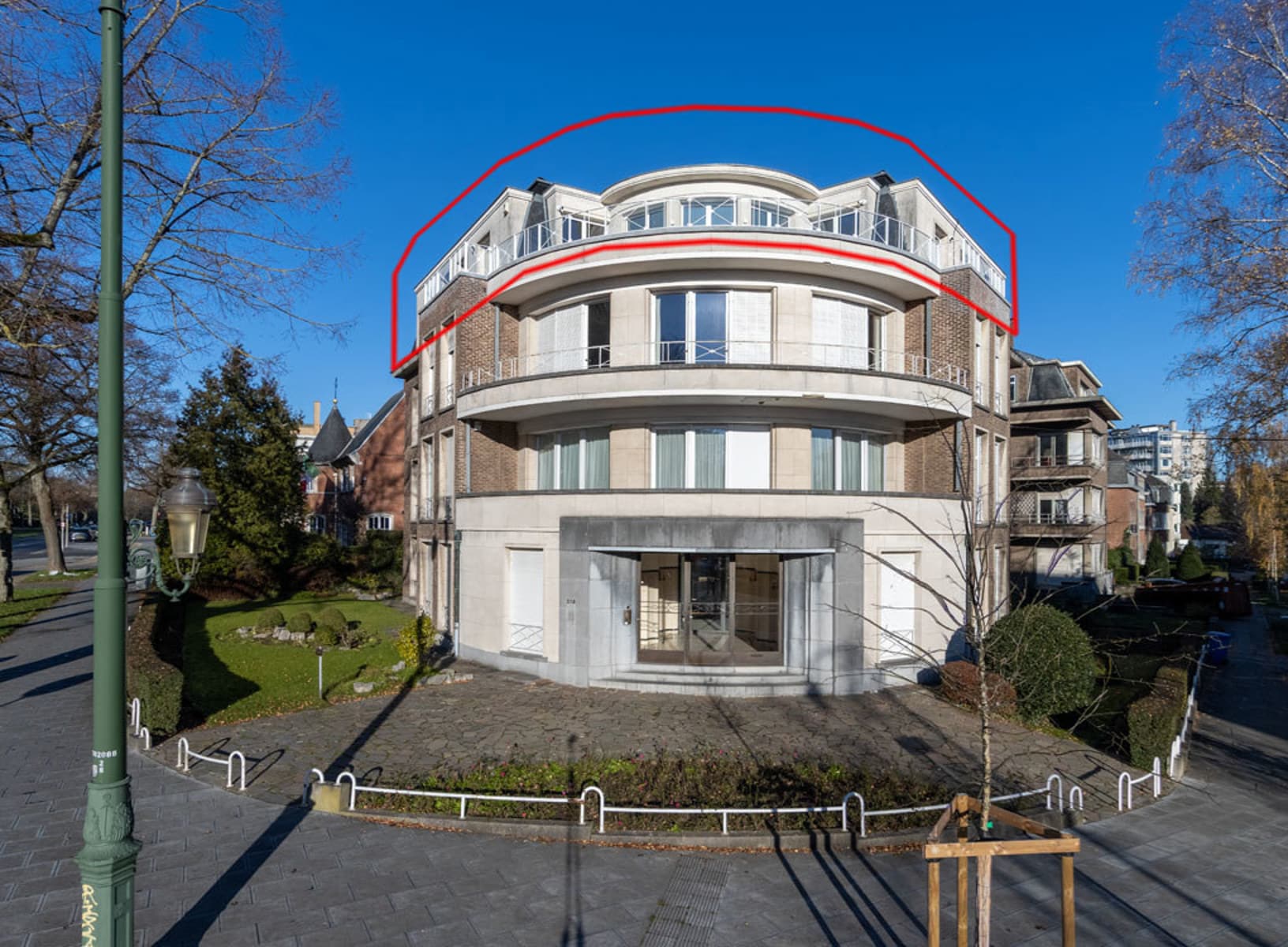 whise photo 24 Curved, beige brick apartment building with glass balconies on a sunny street.