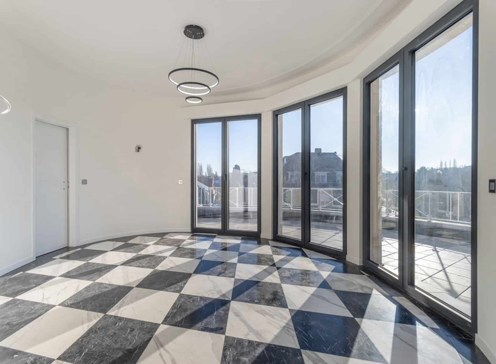 whise photo 4 Bright empty living area with curved glass doors and a black-and-white checkerboard marble floor.