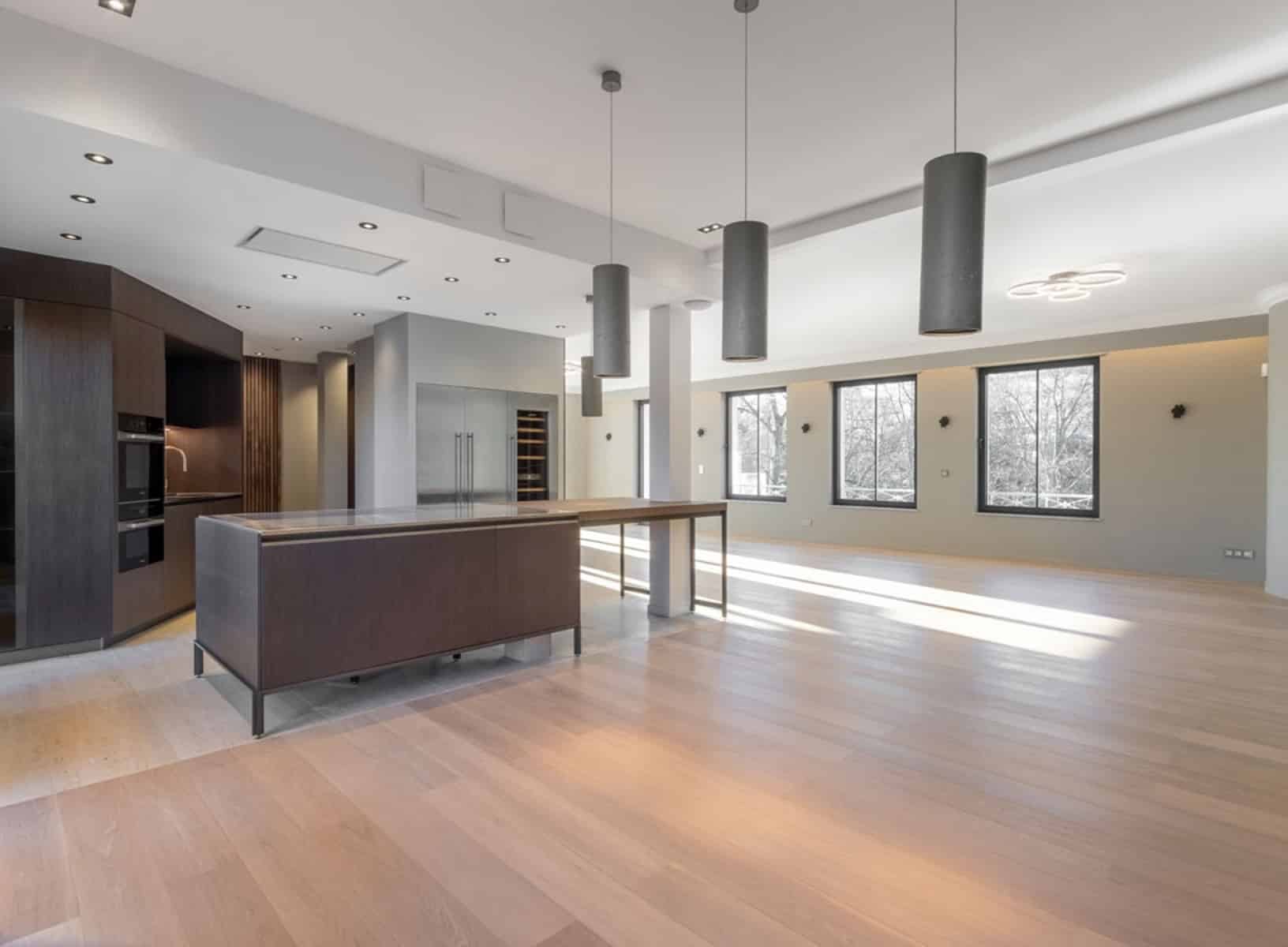 whise photo 11 Open-concept kitchen with a dark wood island, built-in ovens, and three cylindrical pendant lights over a bright, spacious room