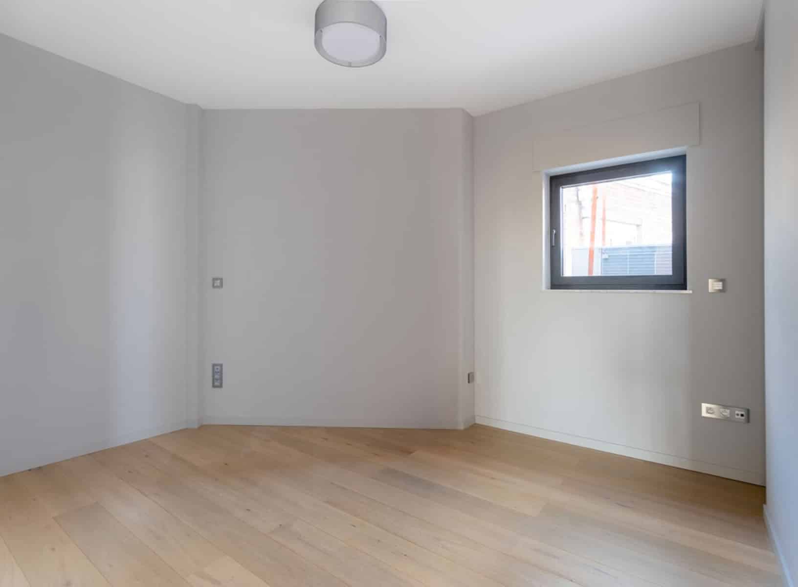 Pièce Lumineuse avec Parquet Clair – You Real Estate Agency Pièce lumineuse d’appartement neuf avec parquet clair et fenêtre.