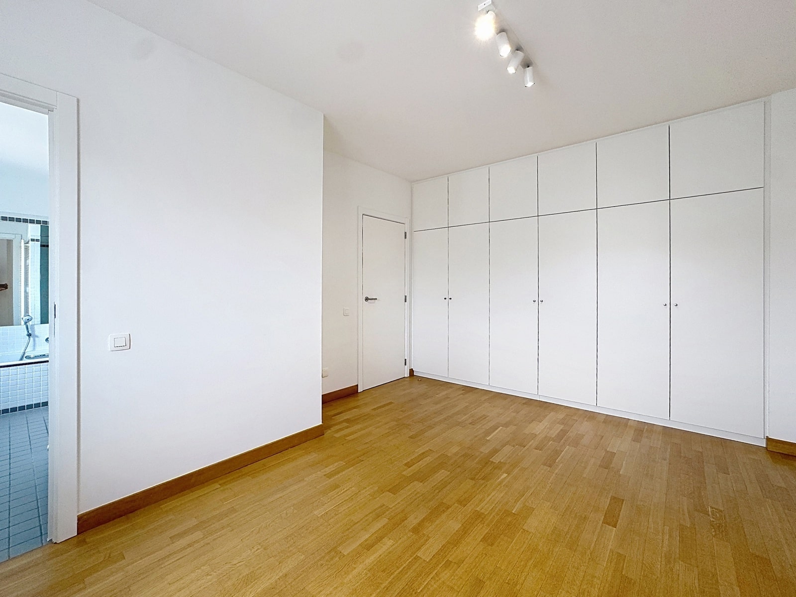 whise photo 6 A bright, empty room with built-in white closets along the right wall and a wooden floor