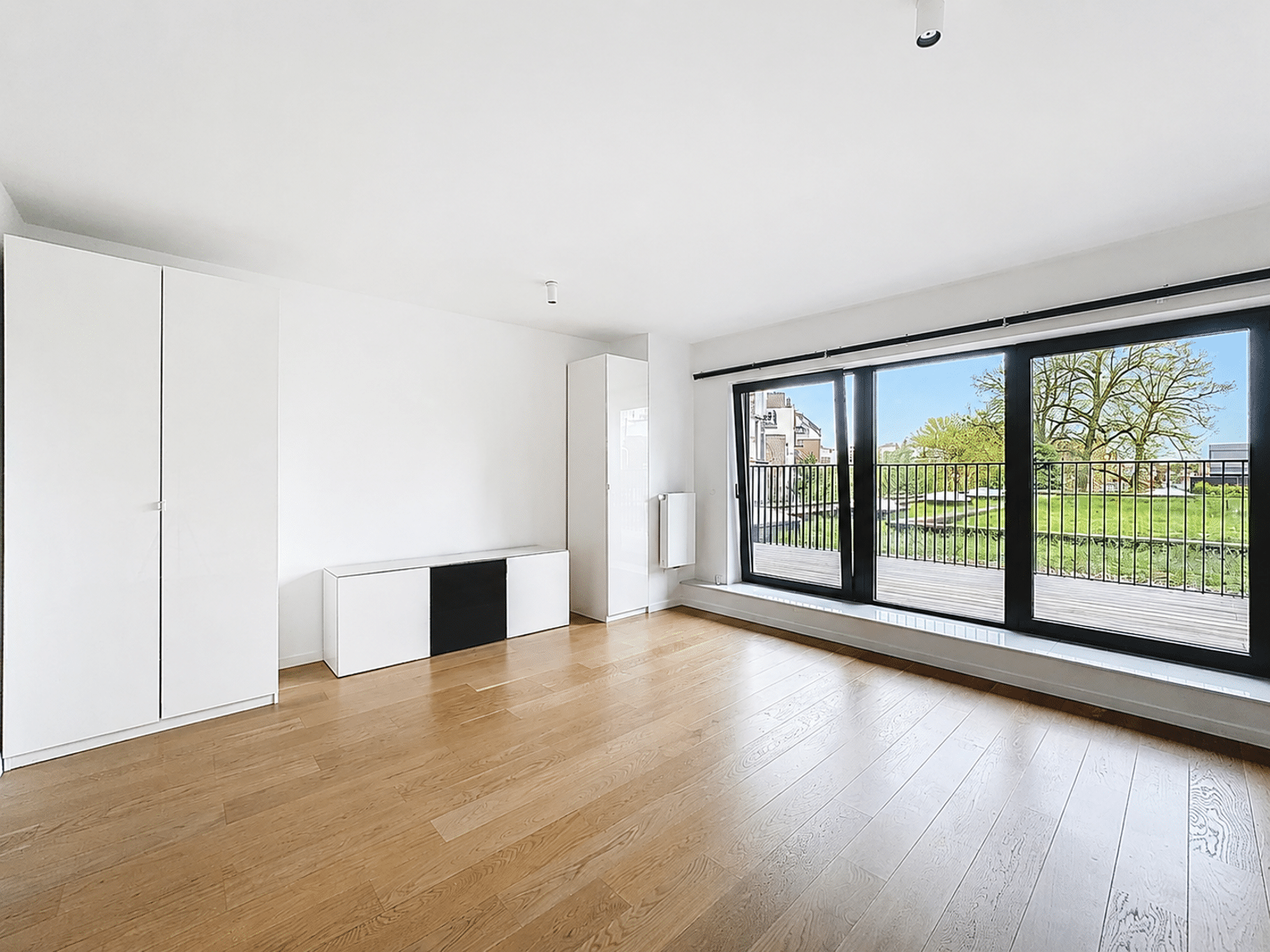 Salon Lumineux avec Terrasse – You Real Estate Agency Salon lumineux d’appartement moderne avec parquet, baies vitrées et terrasse.