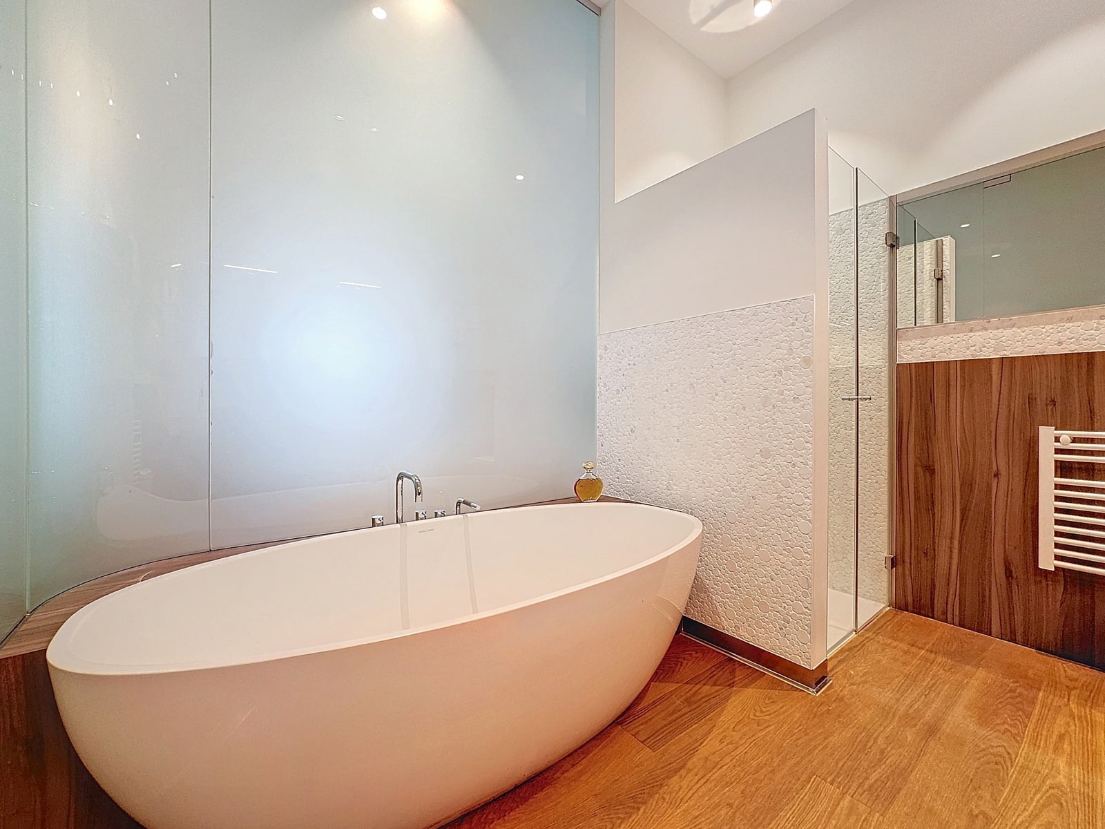 Salle de Bains avec Baignoire Îlot – You Real Estate Agency Salle de bains moderne avec baignoire îlot, douche vitrée et parquet bois.