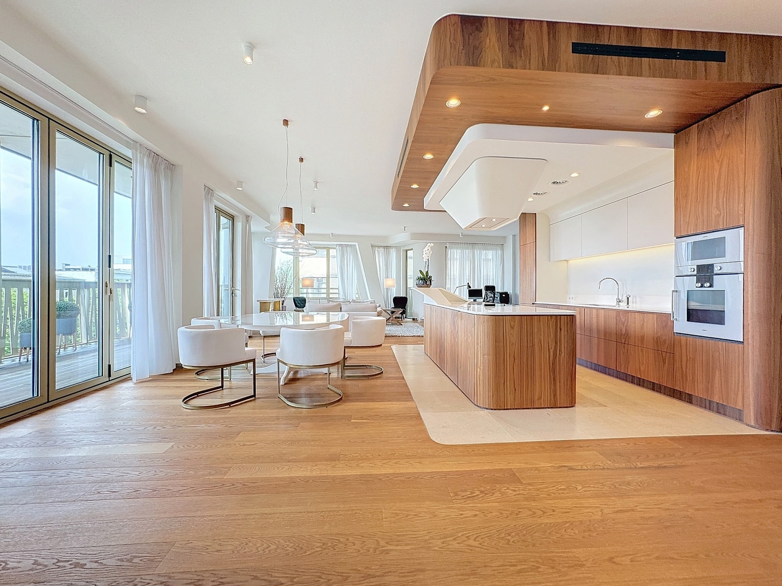whise photo 4 Open-concept kitchen and living area with a wooden island, white cabinets, and large glass doors to the outside.