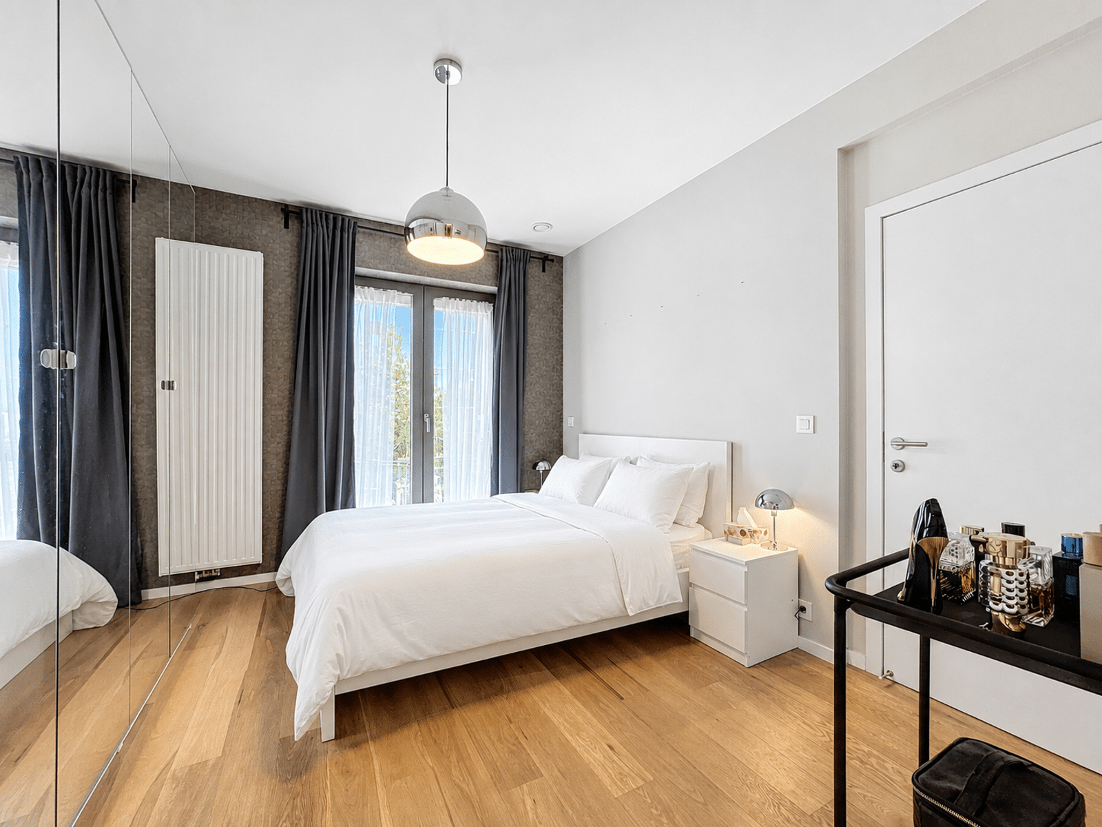 Chambre Lumineuse Avec Dressing – You Real Estate Agency Chambre moderne lumineuse avec lit blanc, dressing miroir et parquet dans appartement.