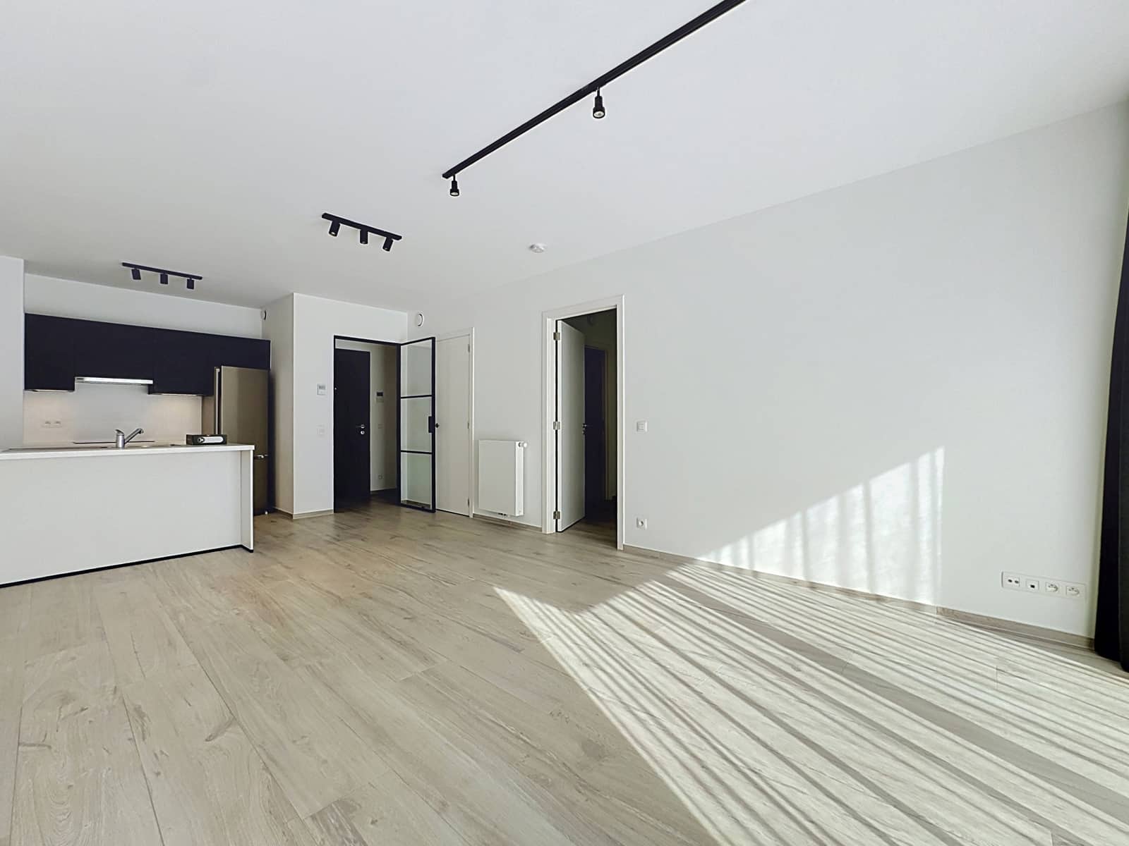 Bright living room with open kitchen - You Real Estate Agency Bright apartment with an open living room, a modern open kitchen, and light-colored hardwood floors.