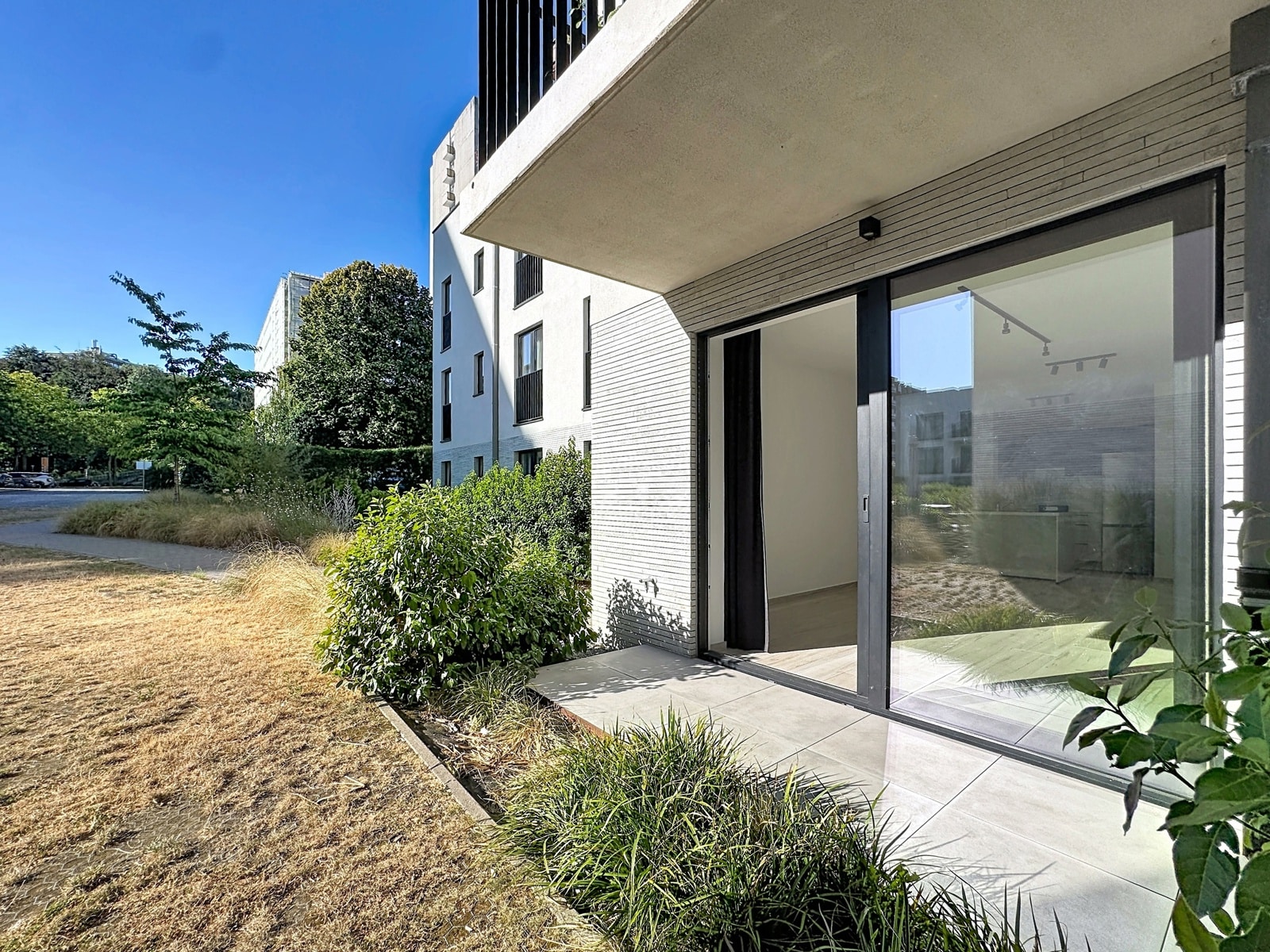 Modern Apartment Terrace – You Real Estate Agency Modern apartment with a private terrace and floor-to-ceiling windows in a contemporary residential complex.