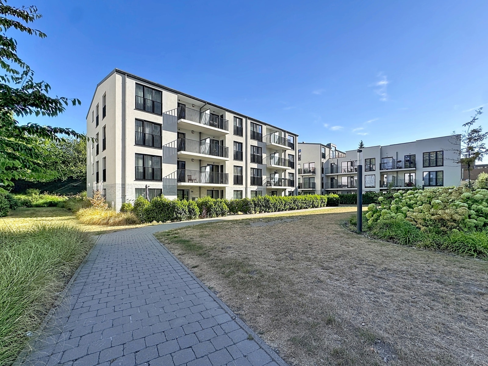 Modern Apartment Building with Balconies – You Real Estate Agency Modern apartment building with balconies, terraces, and a landscaped garden.