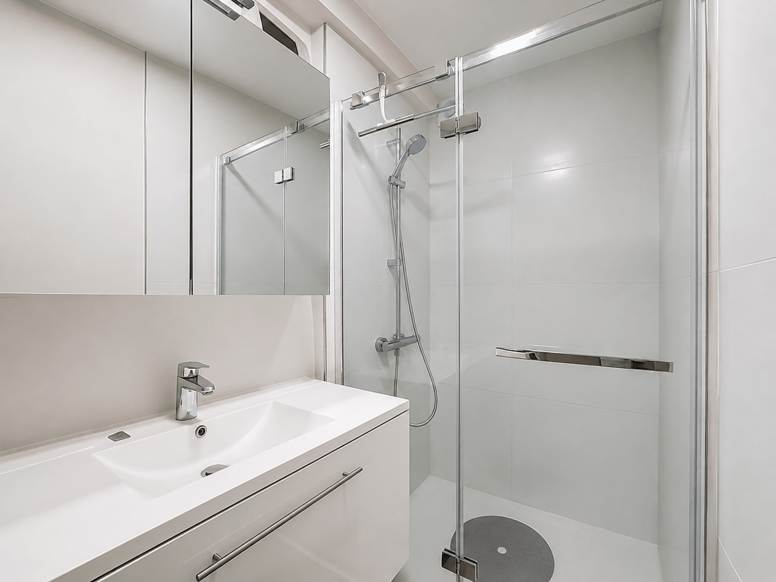 whise photo 5 Modern bathroom with a white vanity, mirror cabinet, and glass shower enclosure.