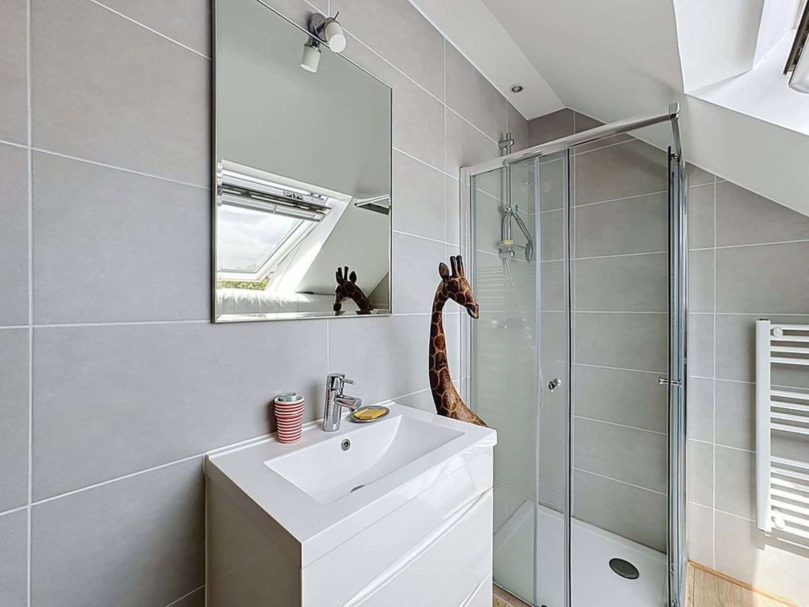 Salle de Bain Moderne Sous Combles – You Real Estate Agency Salle de bain moderne sous combles avec douche vitrée et vasque, appartement lumineux.