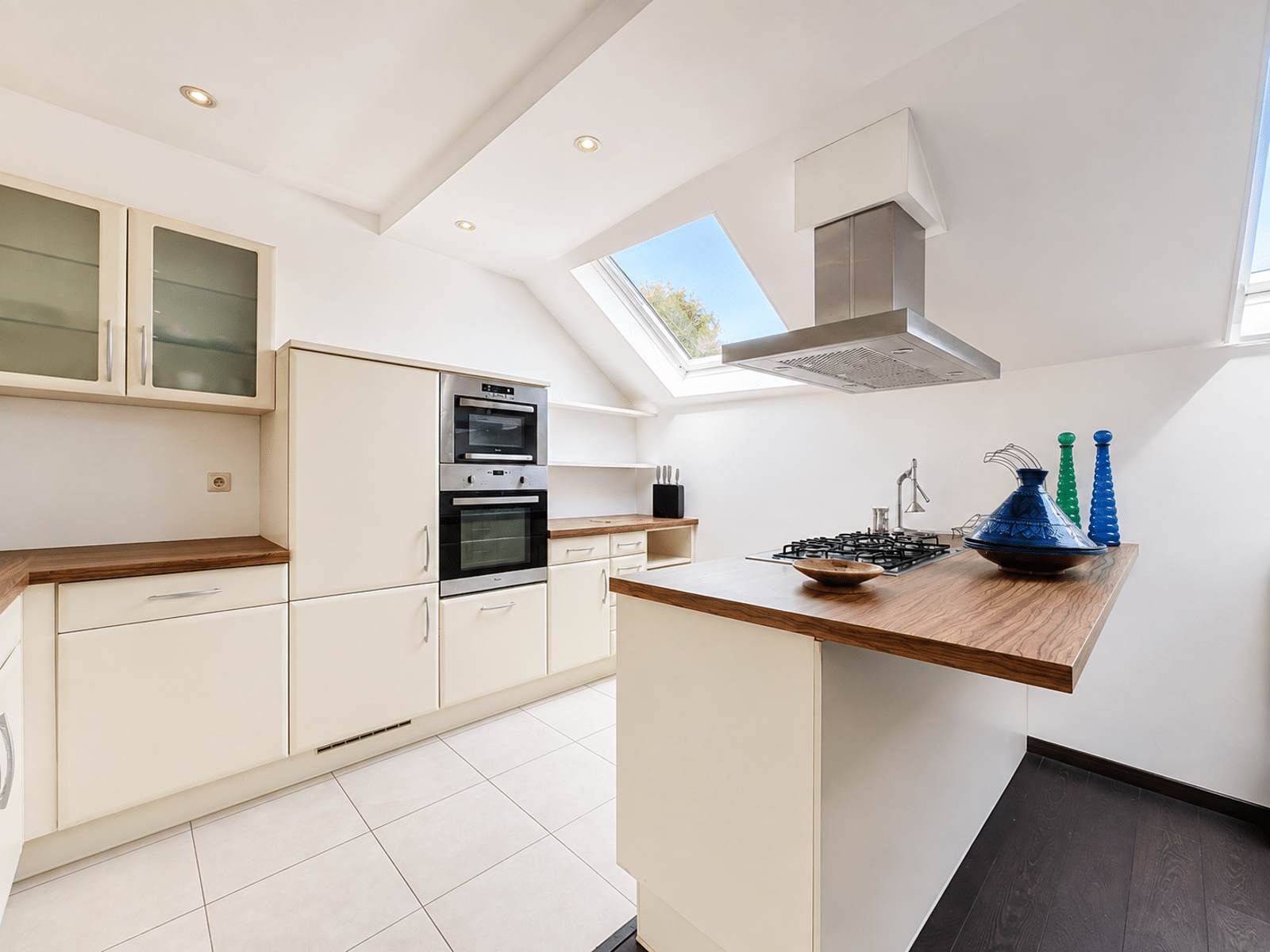 Cuisine Moderne avec Îlot Central – You Real Estate Agency Cuisine moderne lumineuse avec îlot central, plan de travail bois et puits de lumière.
