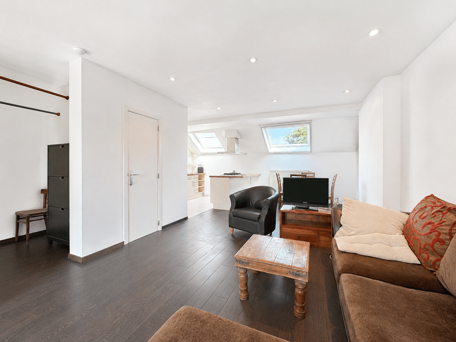 Séjour Mansardé avec Cuisine Ouverte – You Real Estate Agency Appartement mansardé lumineux avec salon cosy, cuisine ouverte et parquet sombre.