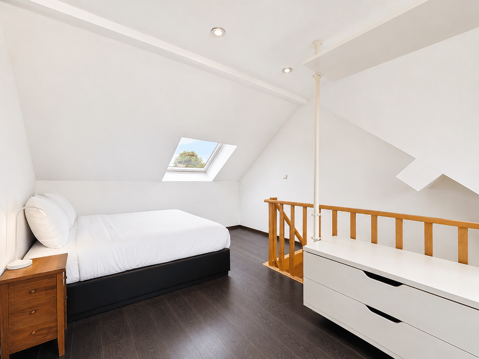 Chambre Mansardée Lumineuse – You Real Estate Agency Chambre mansardée lumineuse avec lit double et fenêtre de toit dans appartement moderne.