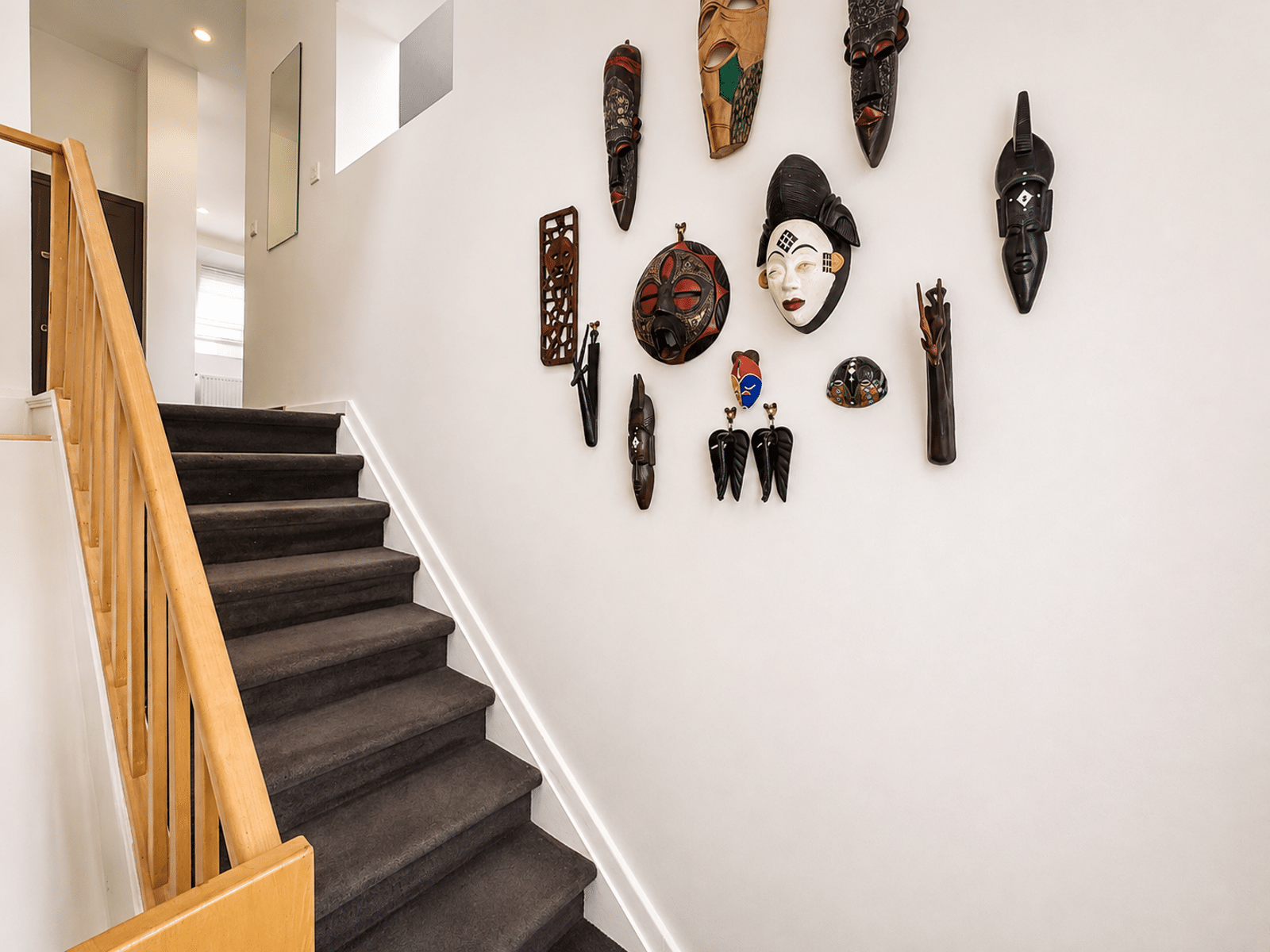 Escalier Moderne avec Masques Muraux – You Real Estate Agency Escalier intérieur moderne d’une maison avec masques décoratifs muraux.