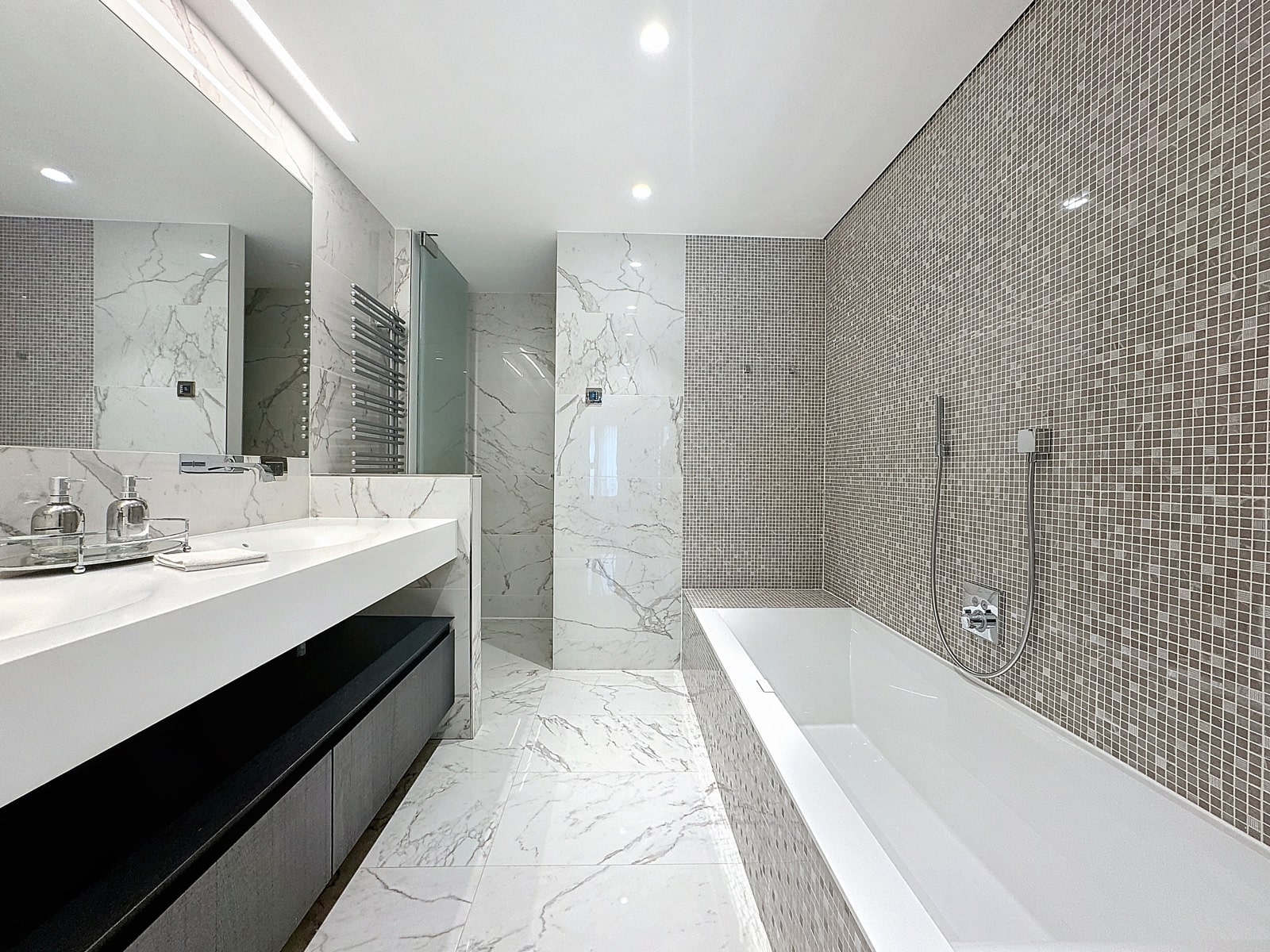 whise photo 18 Modern bathroom with white marble walls, large mirror, double sink, and a white tub along a mosaic-tiled wall; chrome fixtures throughout