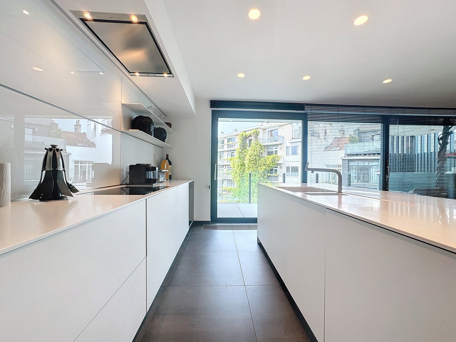 whise photo 13 Bright white galley kitchen with long island, built-in cooktop, and glass door to balcony.