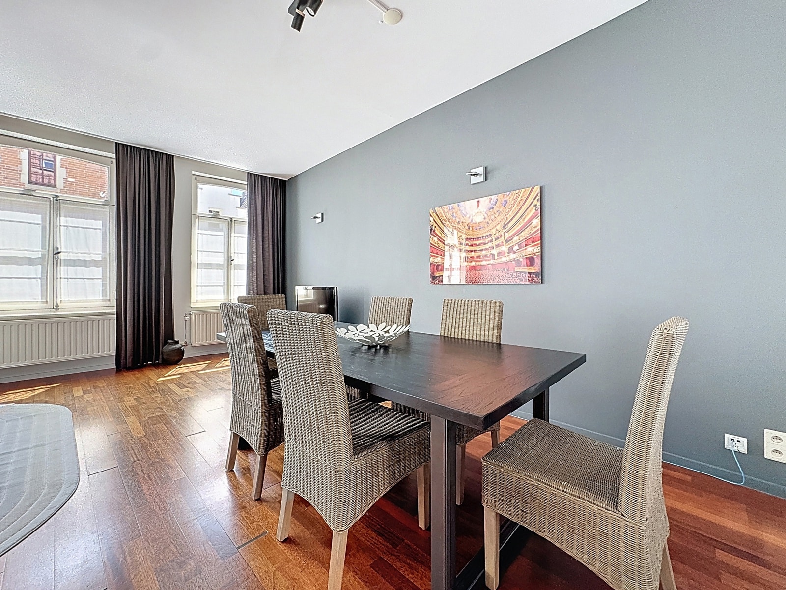 Salle à Manger Moderne avec Parquet – You Real Estate Agency Salle à manger moderne d’appartement avec parquet, grande table et fenêtres lumineuses.