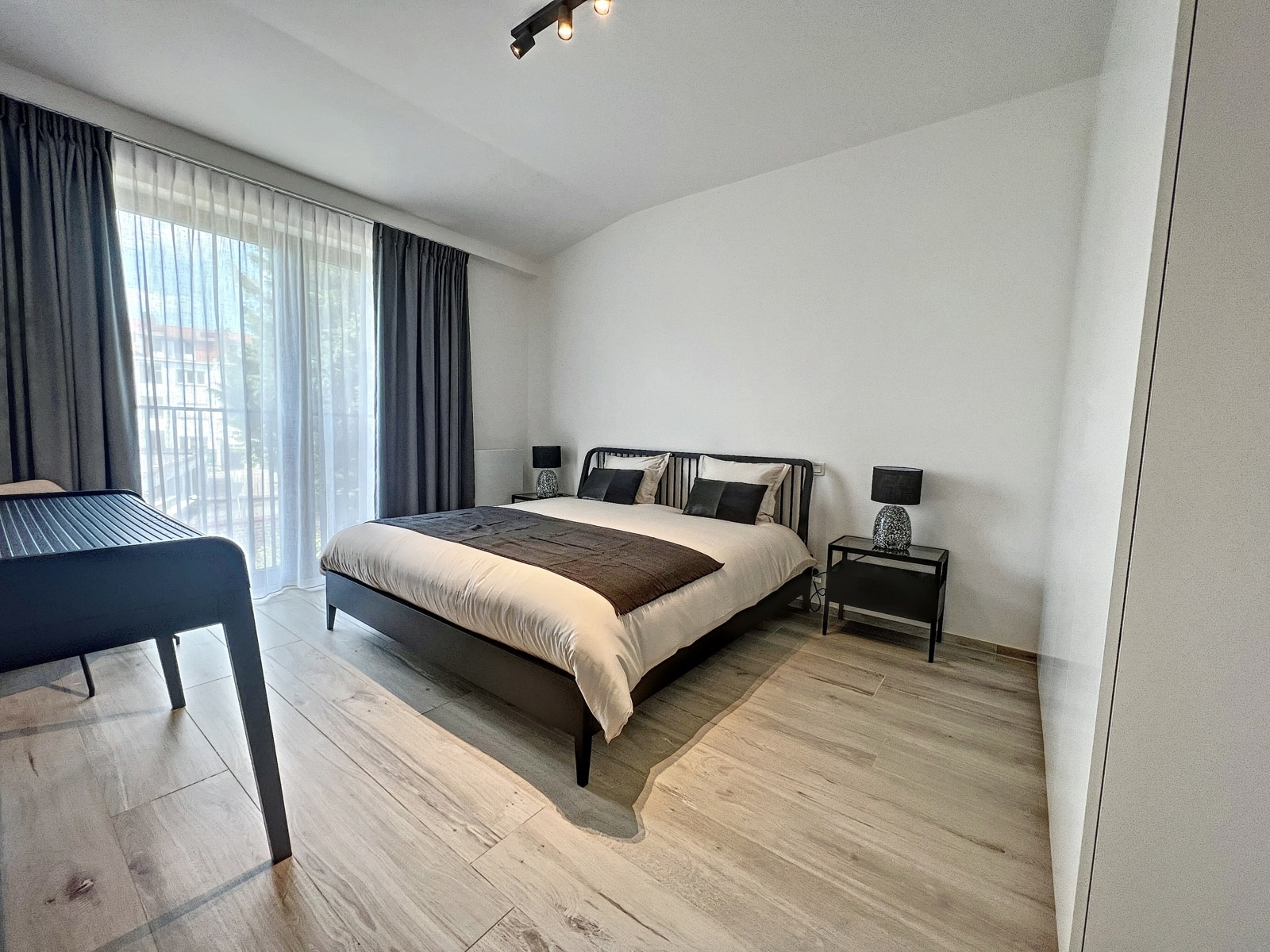 Moderne en lichte slaapkamer - You Real Estate Agency Moderne en lichte slaapkamer in een appartement met een tweepersoonsbed en een groot raam.