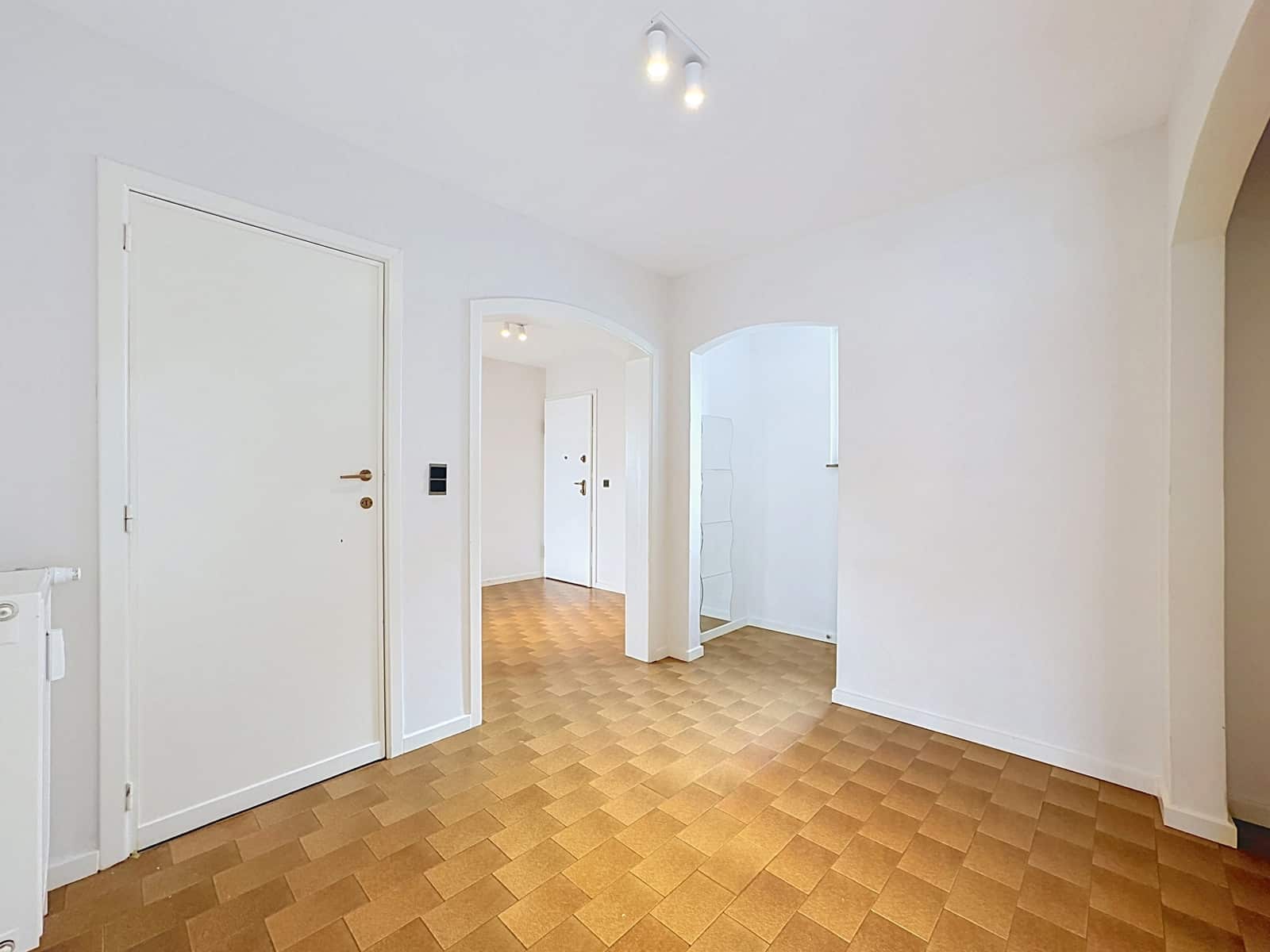 Salon Lumineux Avec Arches – You Real Estate Agency Salon lumineux d’appartement vide avec arches, murs blancs et carrelage beige.