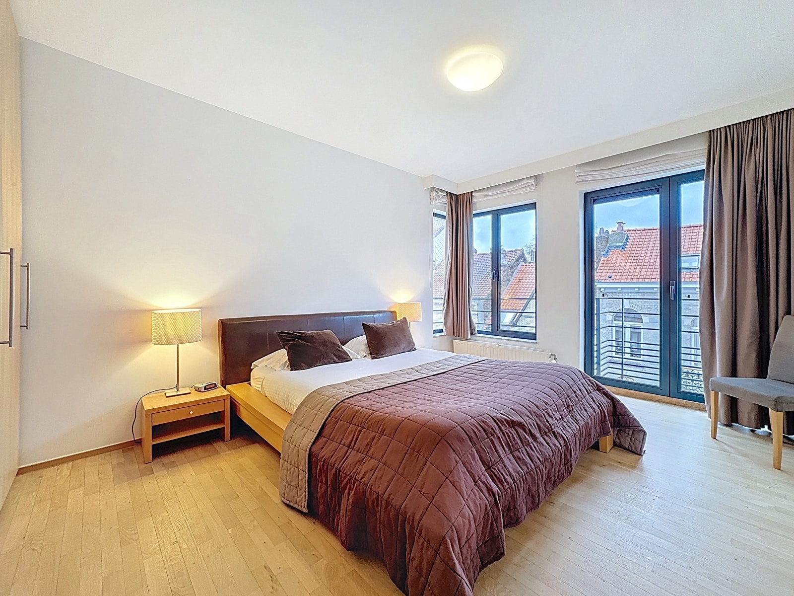 Chambre Lumineuse Avec Balcon – You Real Estate Agency Chambre lumineuse d’appartement avec lit double, balcon et parquet clair.
