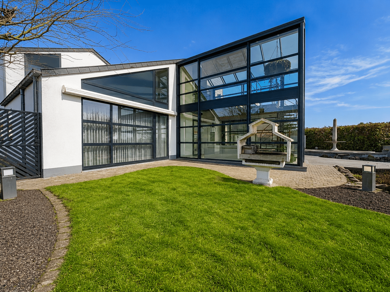 Modern Facade with Garden – You Real Estate Agency Contemporary home with a glass facade, a terrace, and a landscaped garden.