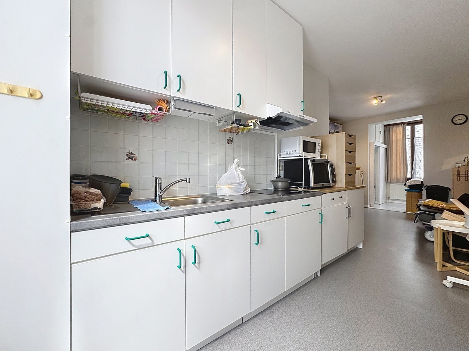 whise photo 10 Long white kitchen with teal cabinet handles, a stainless sink, and appliances along the counter.