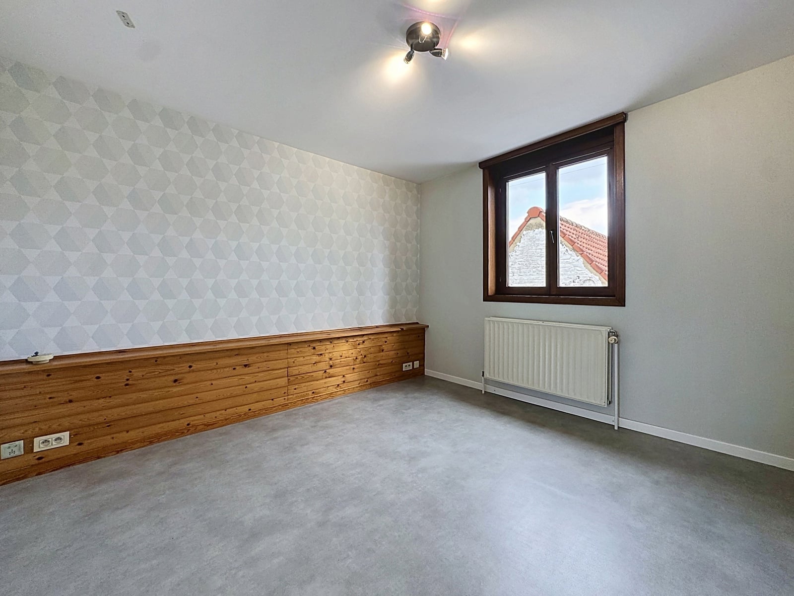 whise photo 18 Empty room with a geometric patterned wall, low wooden wainscoting, window, and radiator visible on the right.