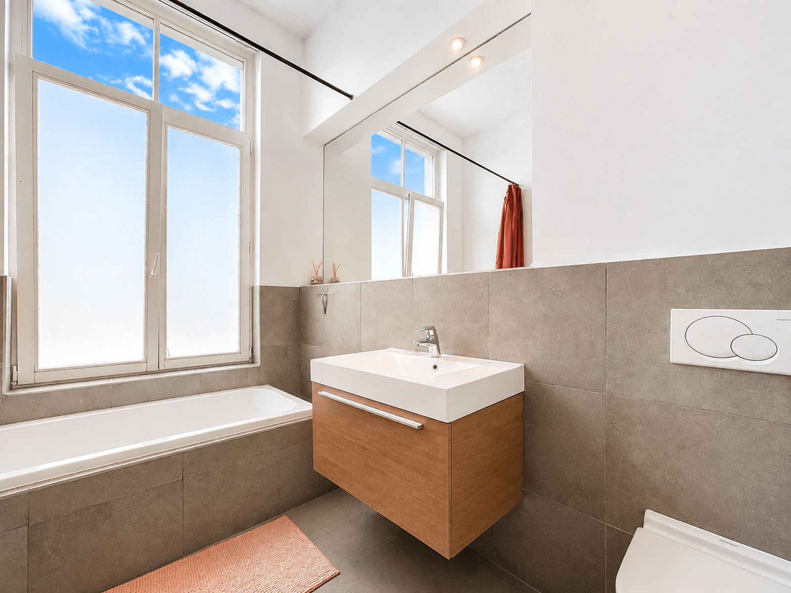 Salle de Bain Moderne et Lumineuse – You Real Estate Agency Salle de bain moderne lumineuse avec baignoire et grande fenêtre en appartement.