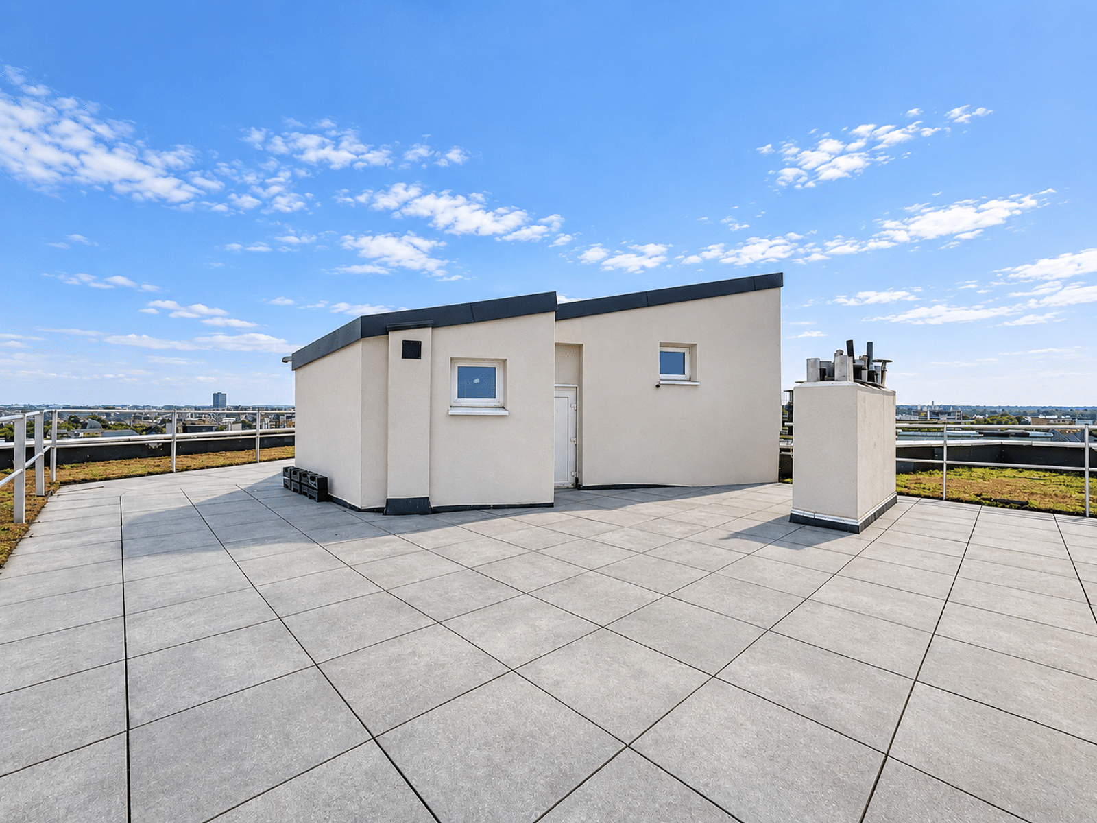 Terrasse Rooftop avec Vue Urbaine – You Real Estate Agency Terrasse rooftop d’appartement moderne avec local technique et vue urbaine.