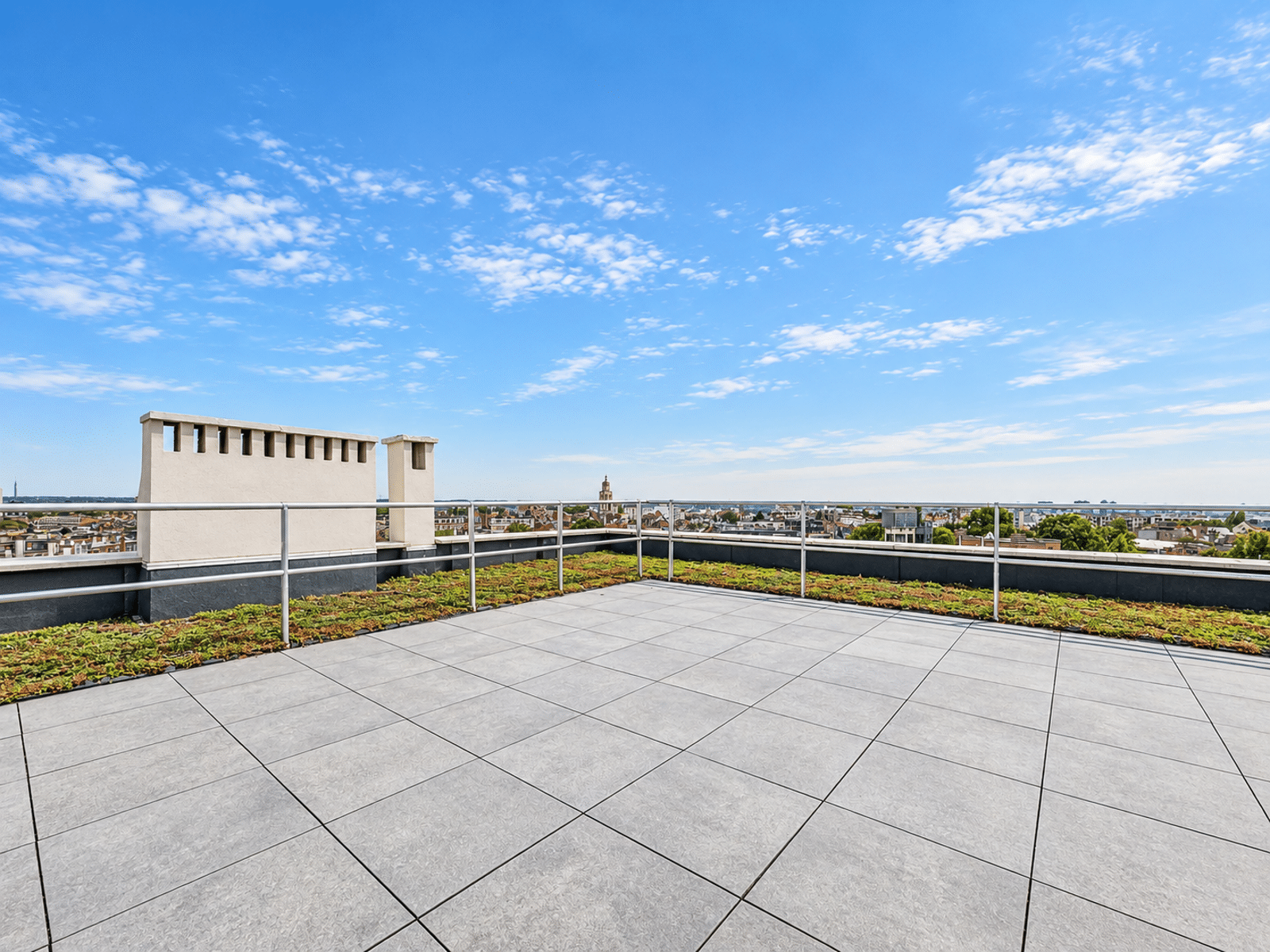 Terrasse Rooftop avec Vue Panoramique – You Real Estate Agency Terrasse rooftop spacieuse avec vue panoramique sur la ville.