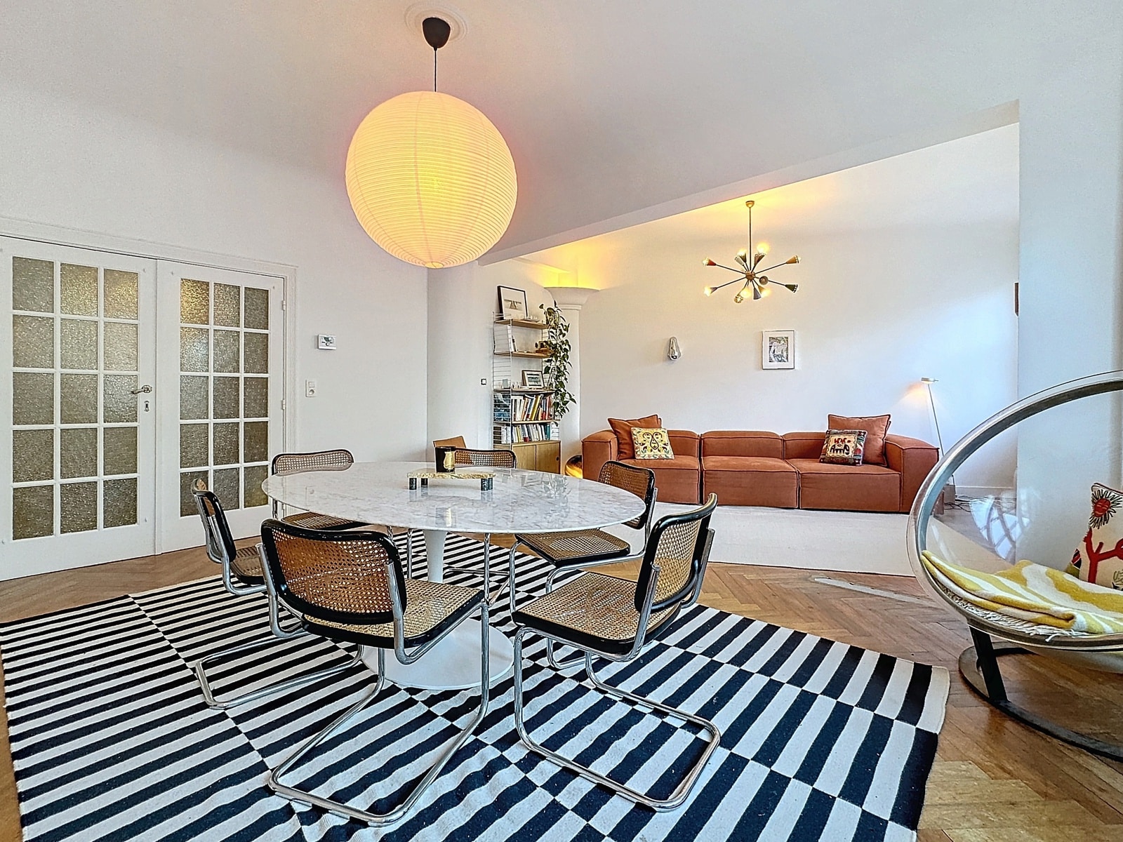 Espace Salon-Salle à Manger Lumineux – You Real Estate Agency Salon et salle à manger modernes avec parquet en chevrons dans un appartement lumineux.