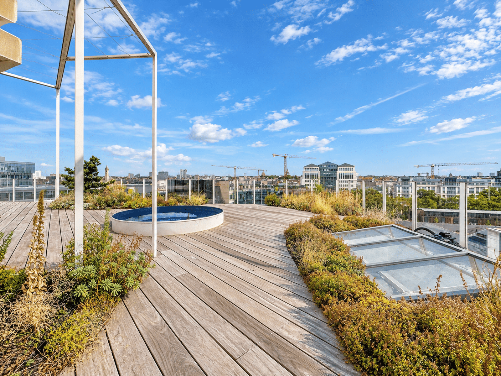 Terrasse Rooftop avec Vue Panoramique – You Real Estate Agency Terrasse rooftop d’appartement avec jacuzzi, jardin paysager et vue panoramique sur la ville.