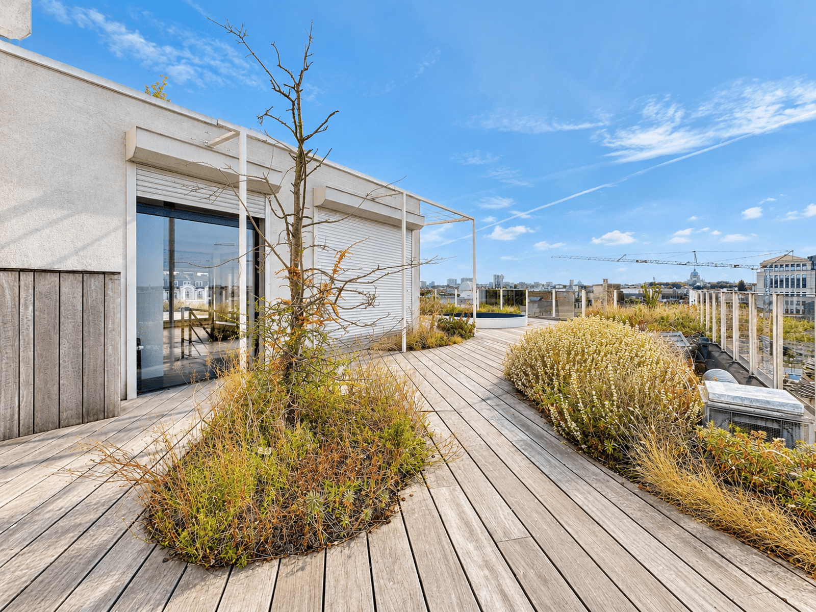 Terrasse Rooftop avec Vue Urbaine – You Real Estate Agency Terrasse rooftop moderne d’appartement avec jardin paysager et vue urbaine.