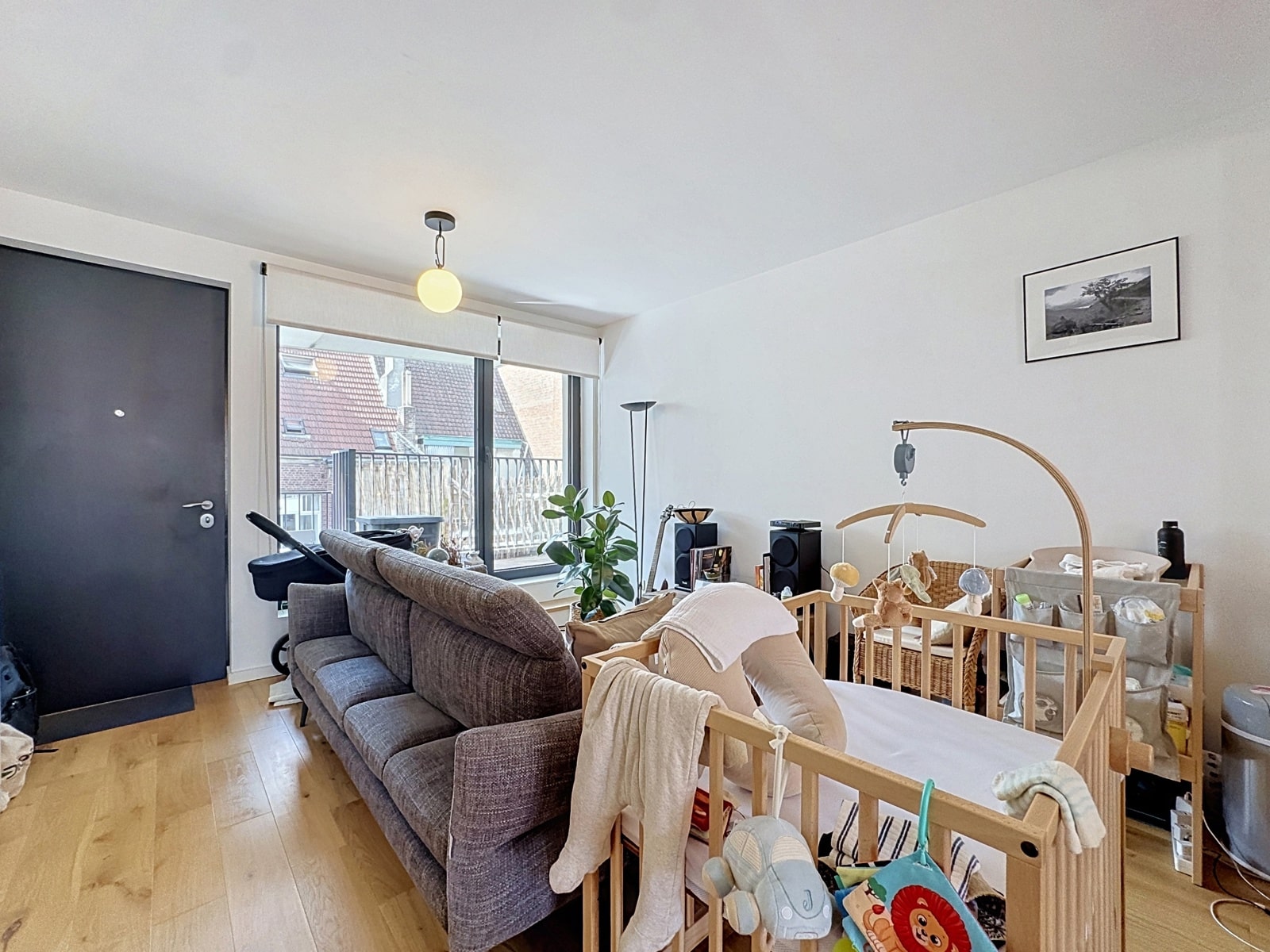 Salon Lumineux avec Coin Bébé – You Real Estate Agency Salon lumineux avec coin bébé, parquet clair et balcon dans un appartement.
